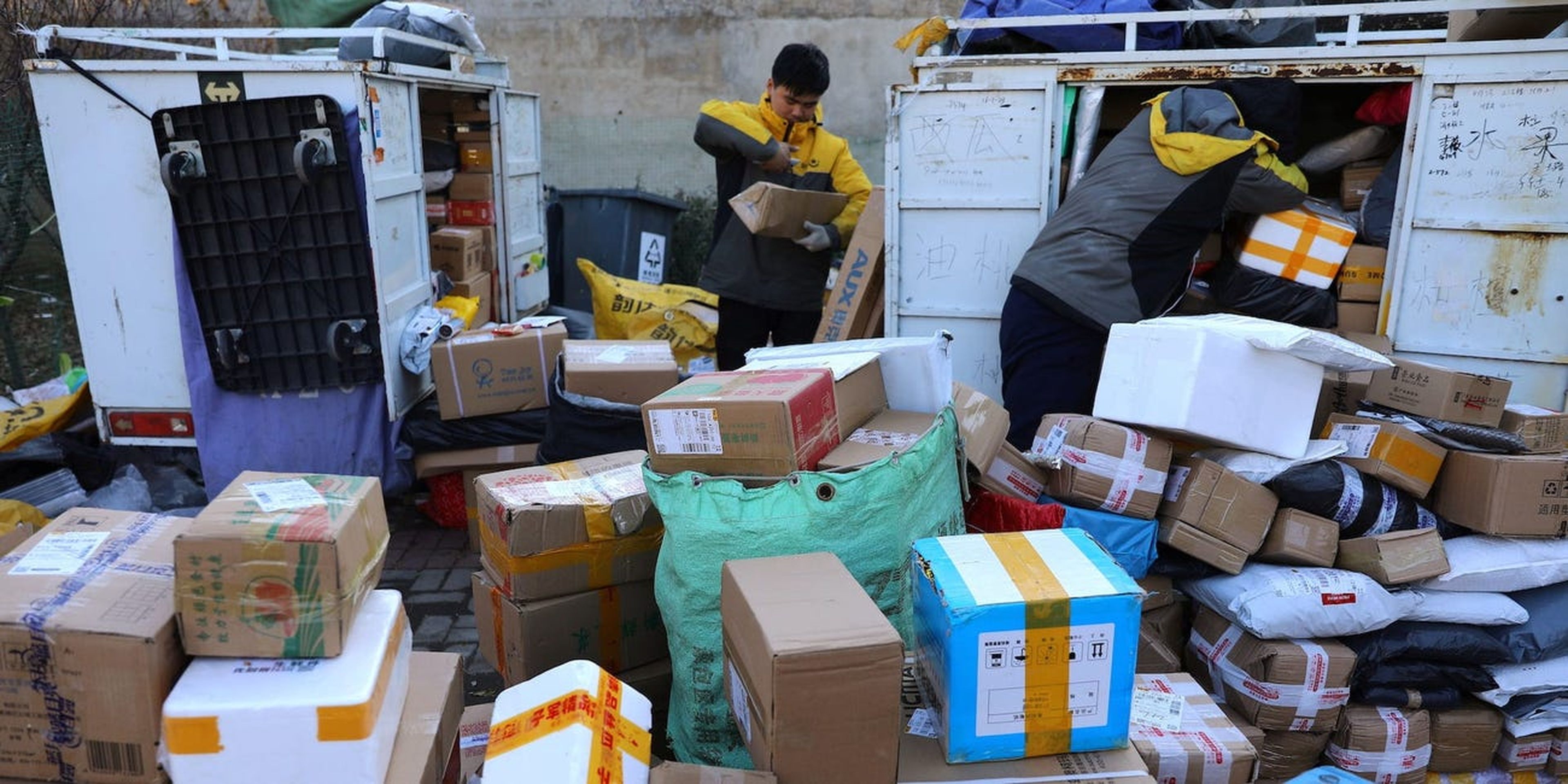 Unos repartidores clasifican paquetes en una estación logística improvisada en Pekín, China.
