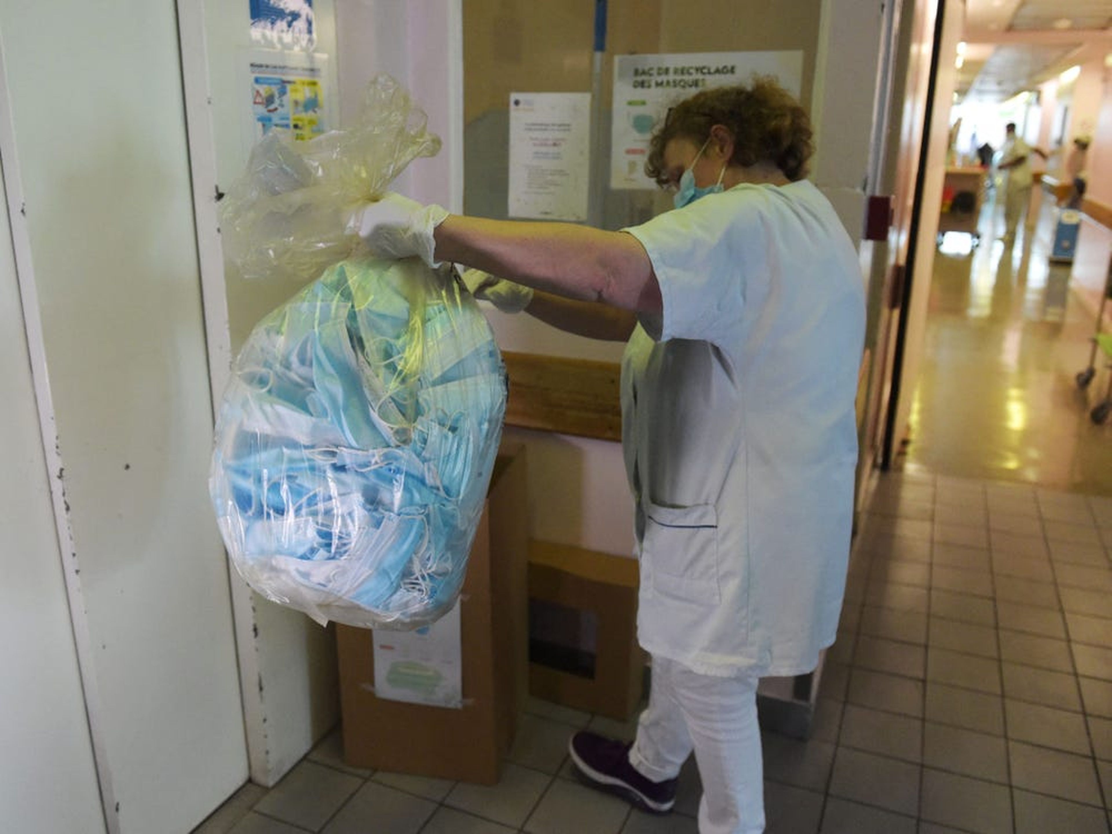 Una enfermera sostiene una bolsa de basura con mascarillas usadas.