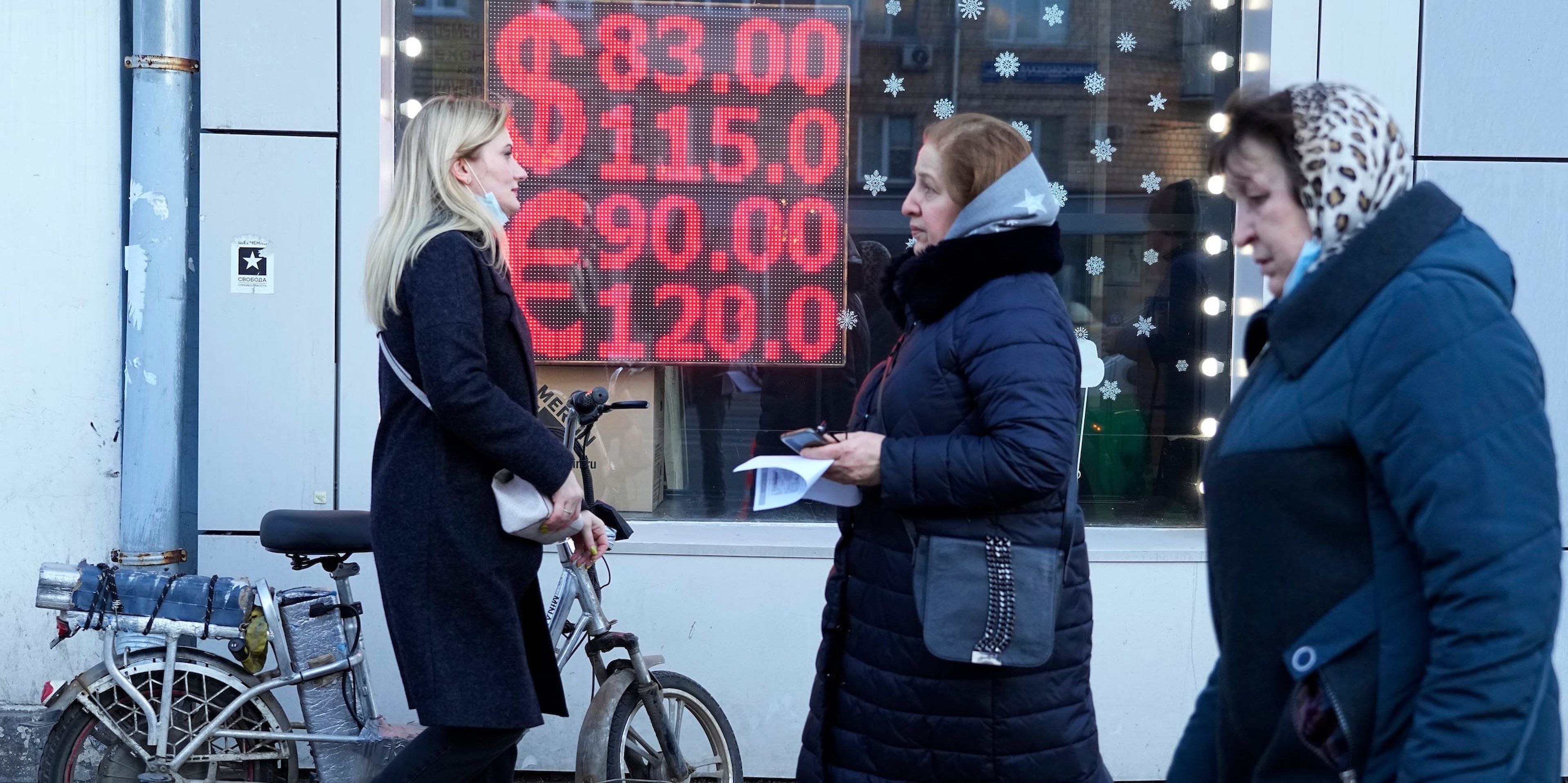 Varias personas caminan frente a una pantalla de una casa de cambio en la que se muestran los tipos de cambio del dólar estadounidense y el euro a los rublos rusos en el centro de Moscú, Rusia, el lunes 28 de febrero de 2022.