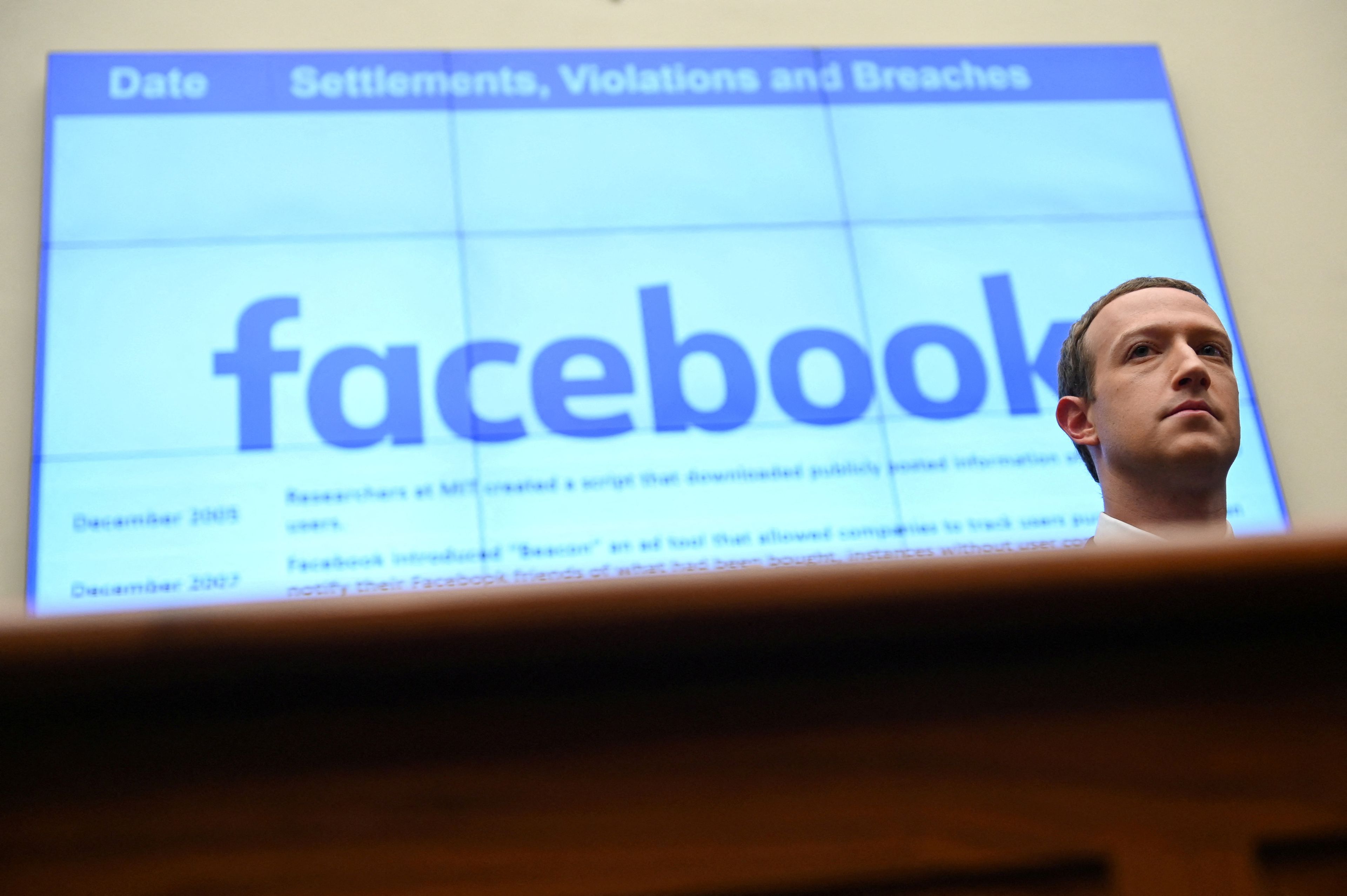 Mark Zuckerberg con un logo de Facebook detrás
