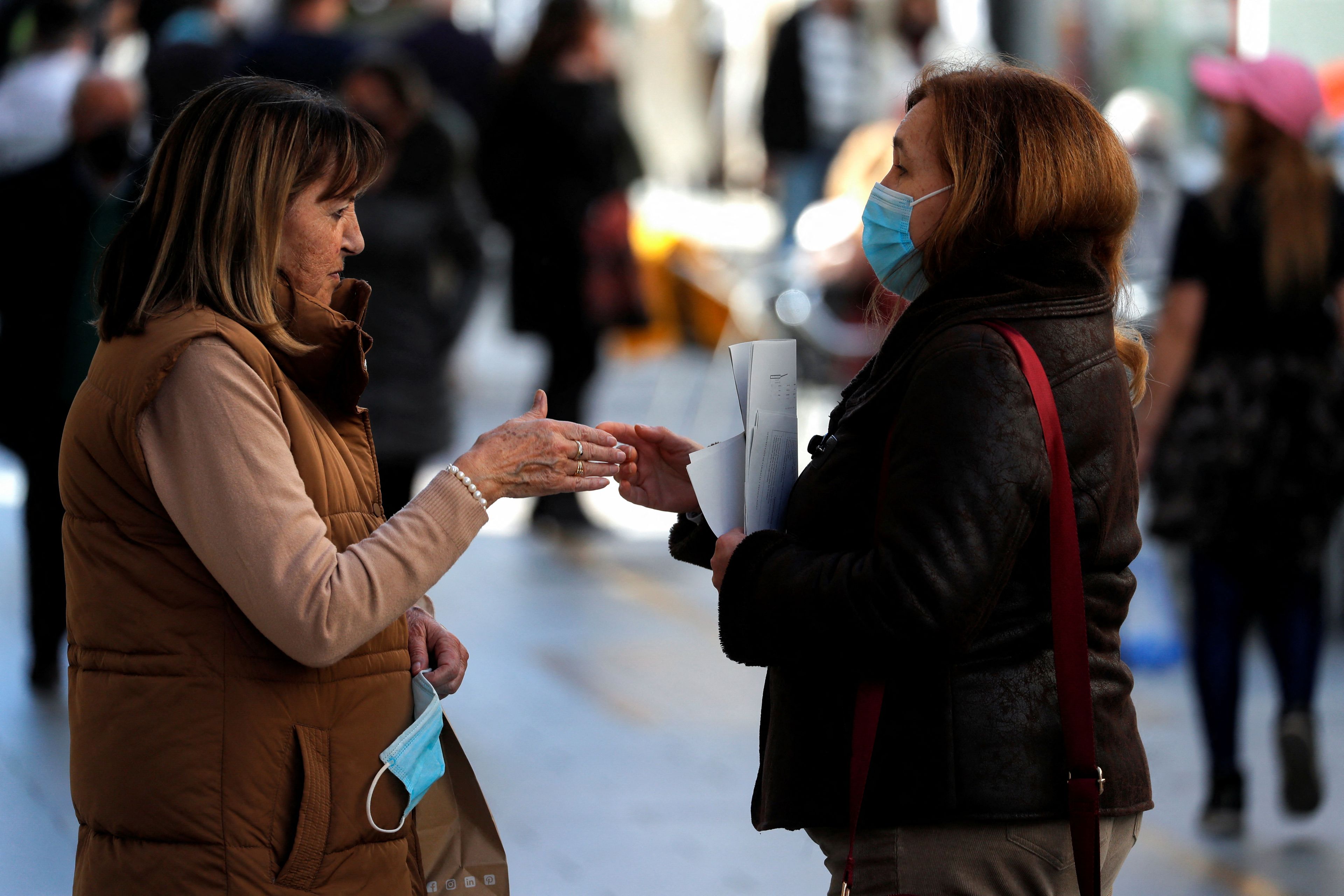 Mujeres hablando en la calle con y sin mascarilla.