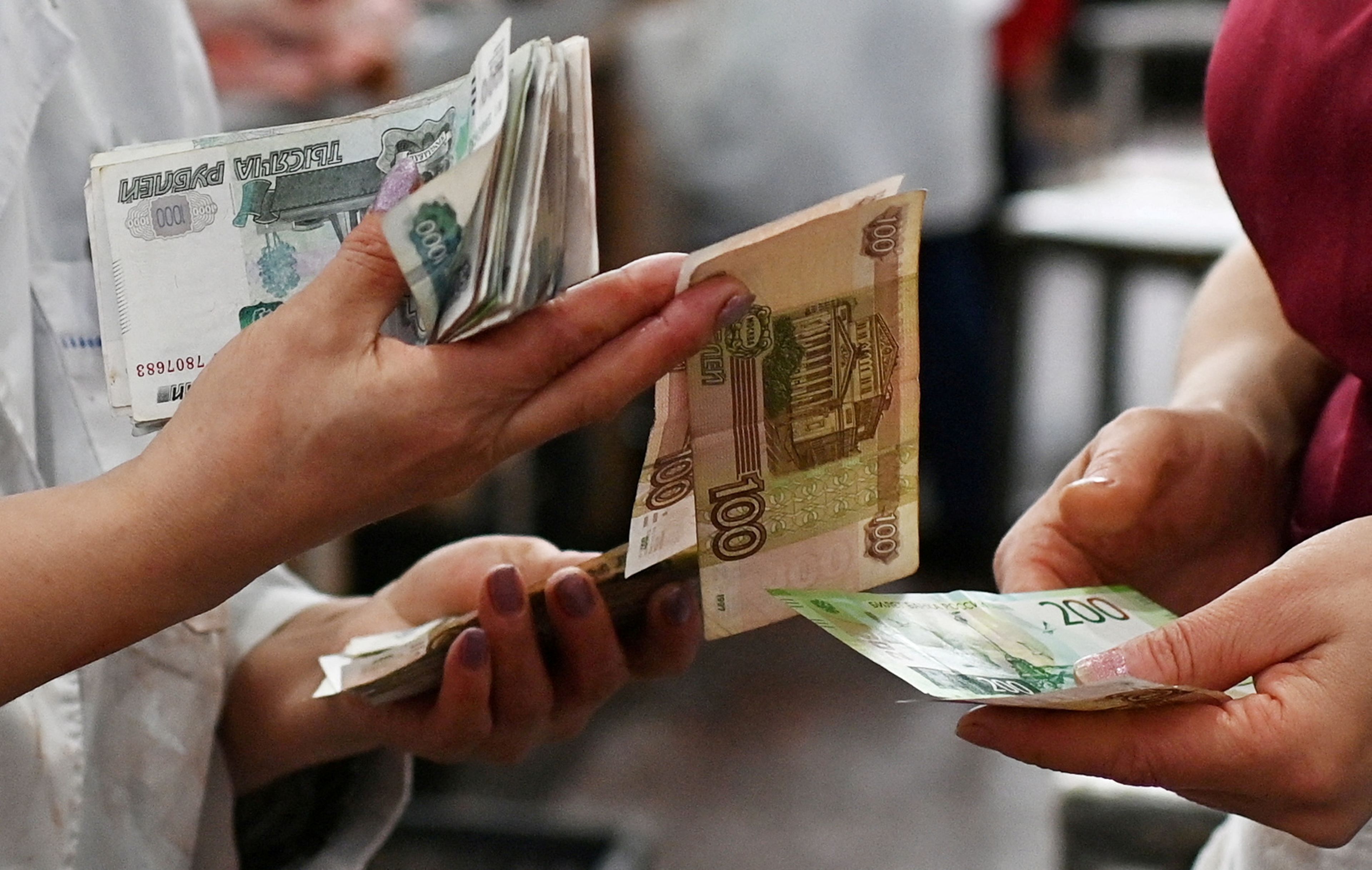 Unos vendedores cuentan billetes de rublos rusos en un mercado de Omsk, Rusia