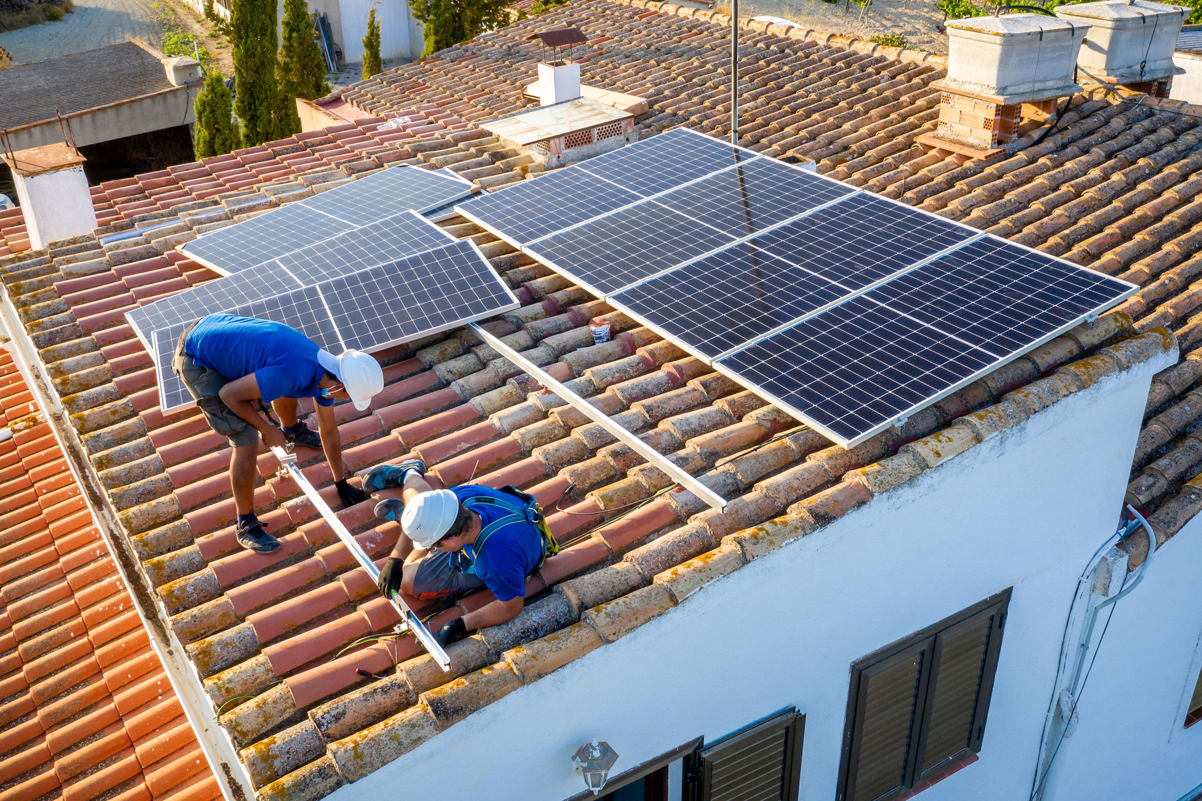 2 personas instalan paneles solares.