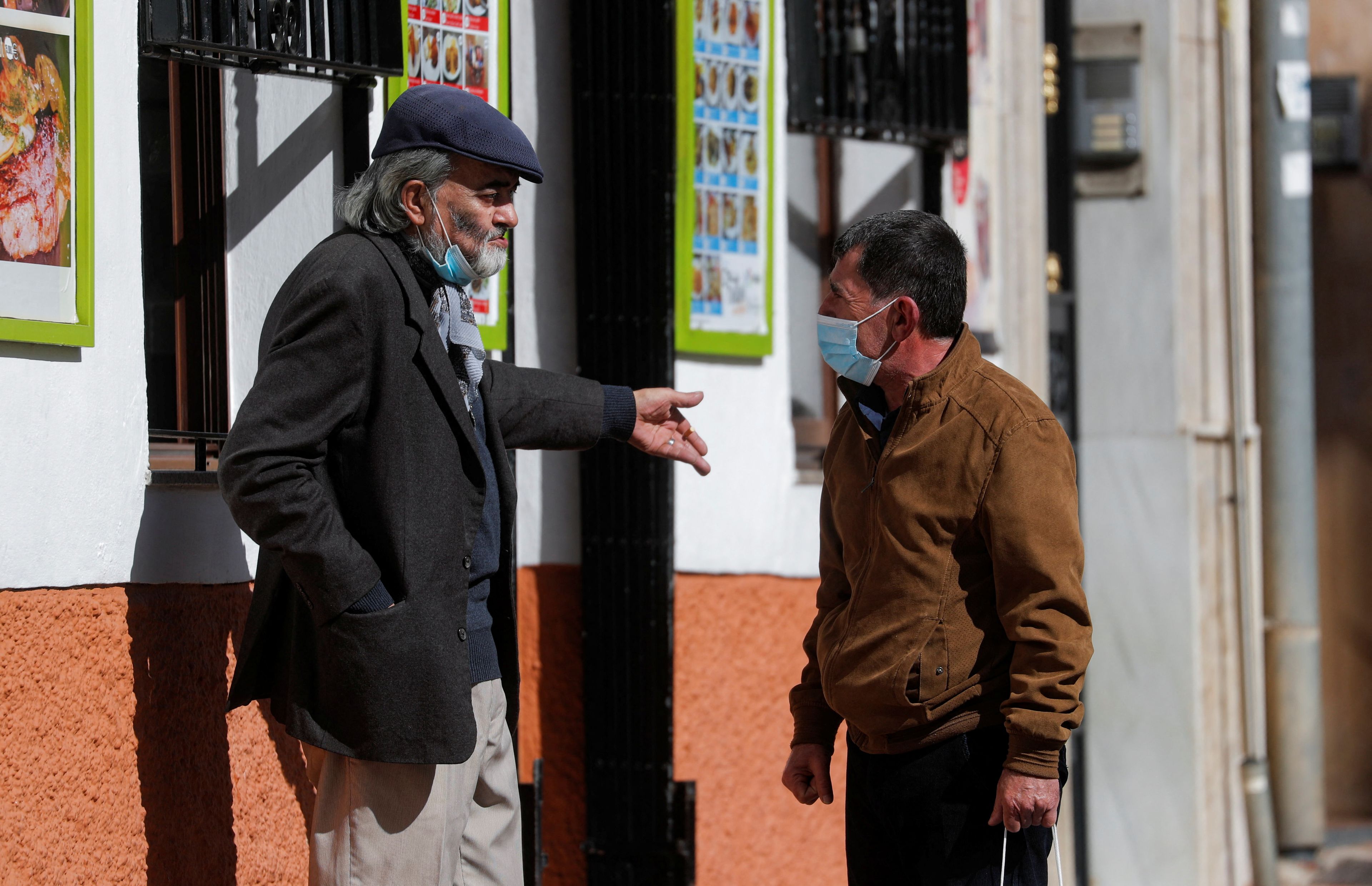 Dos hombres mayores conversan, en pandemia COVID-19