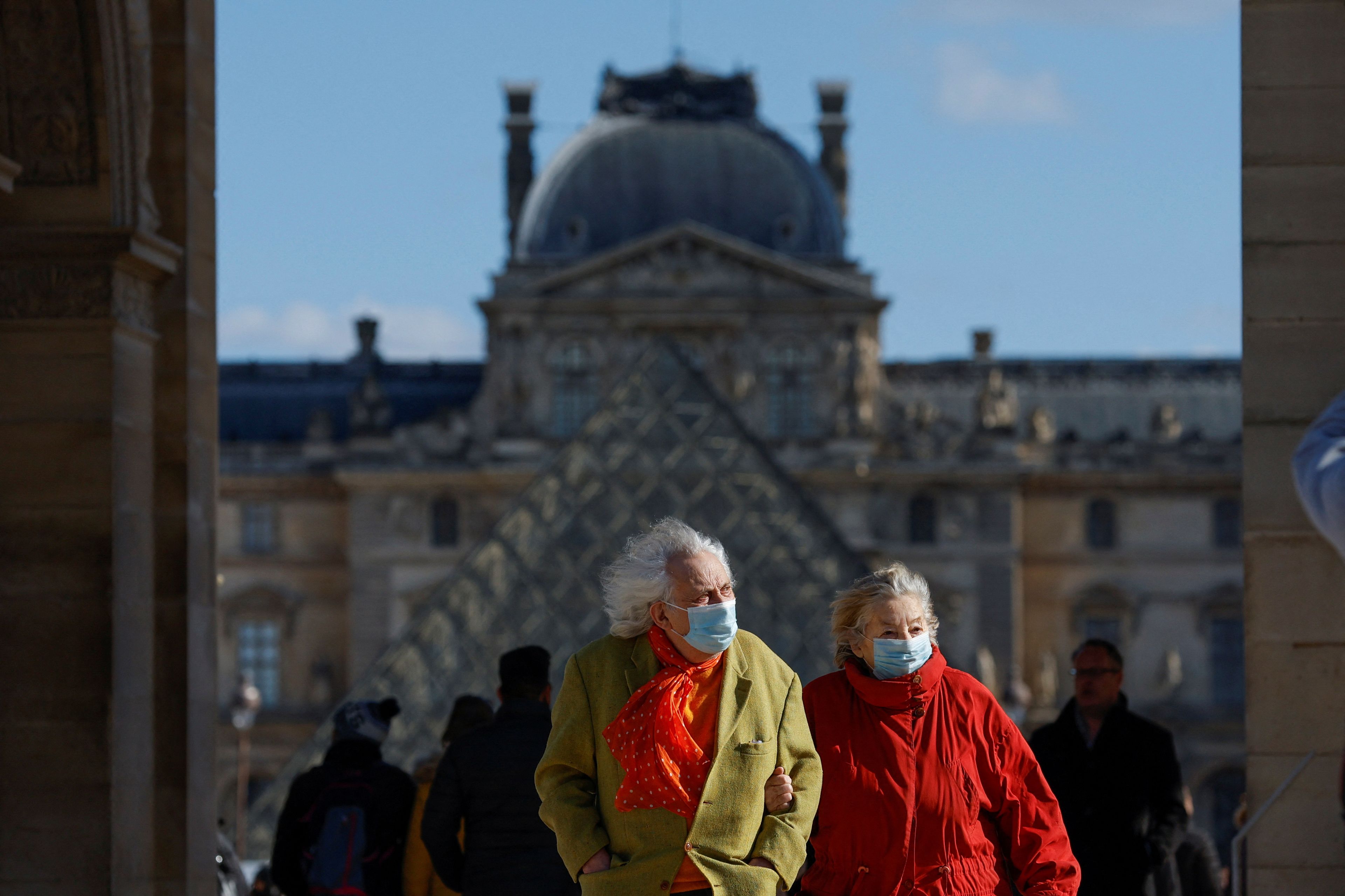 Dos personas mayores pasean en París, Francia, con mascarilla por COVID-19