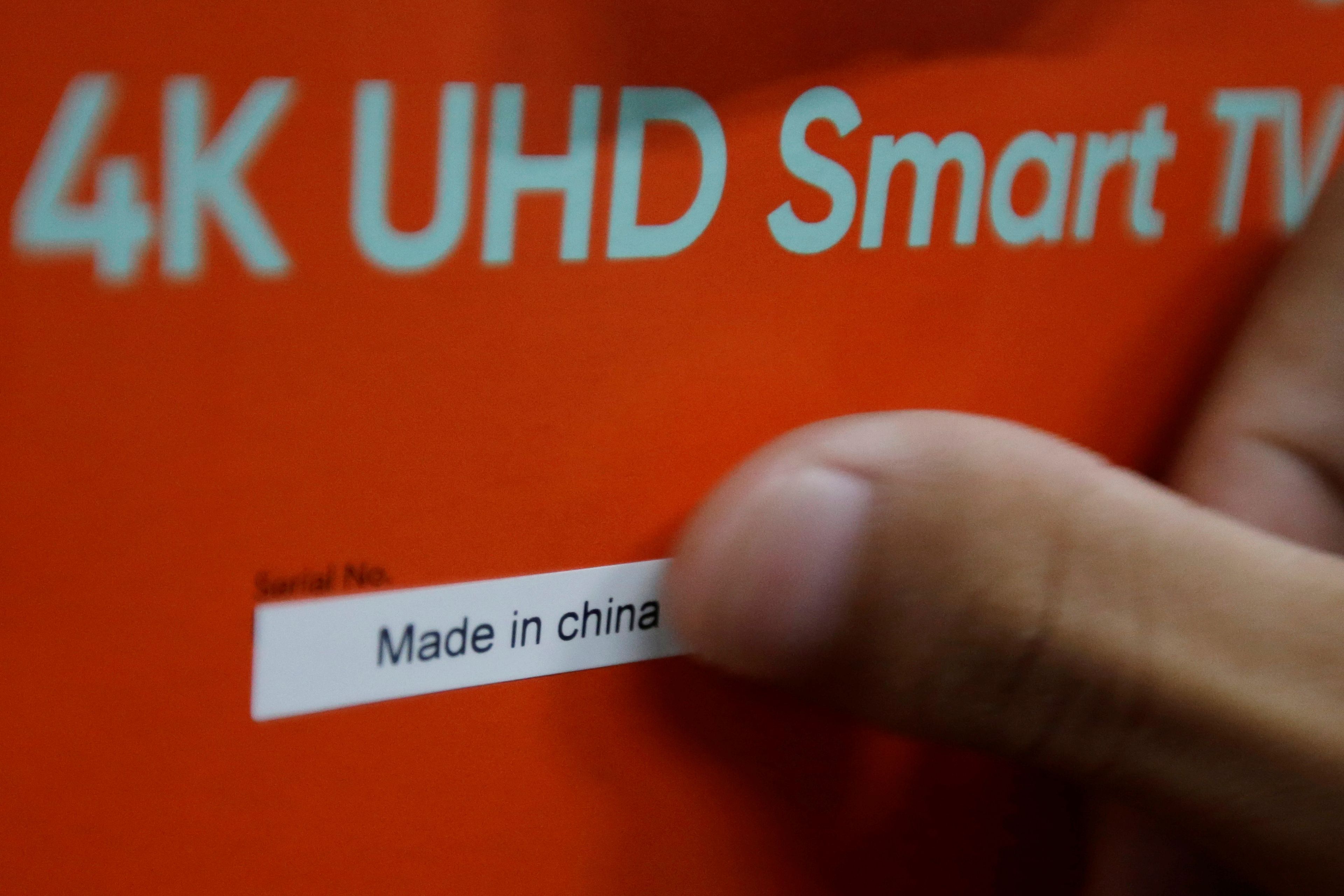 Un empleado pega una pegatina "Made in China" en la caja de un televisor inteligente en una fábrica