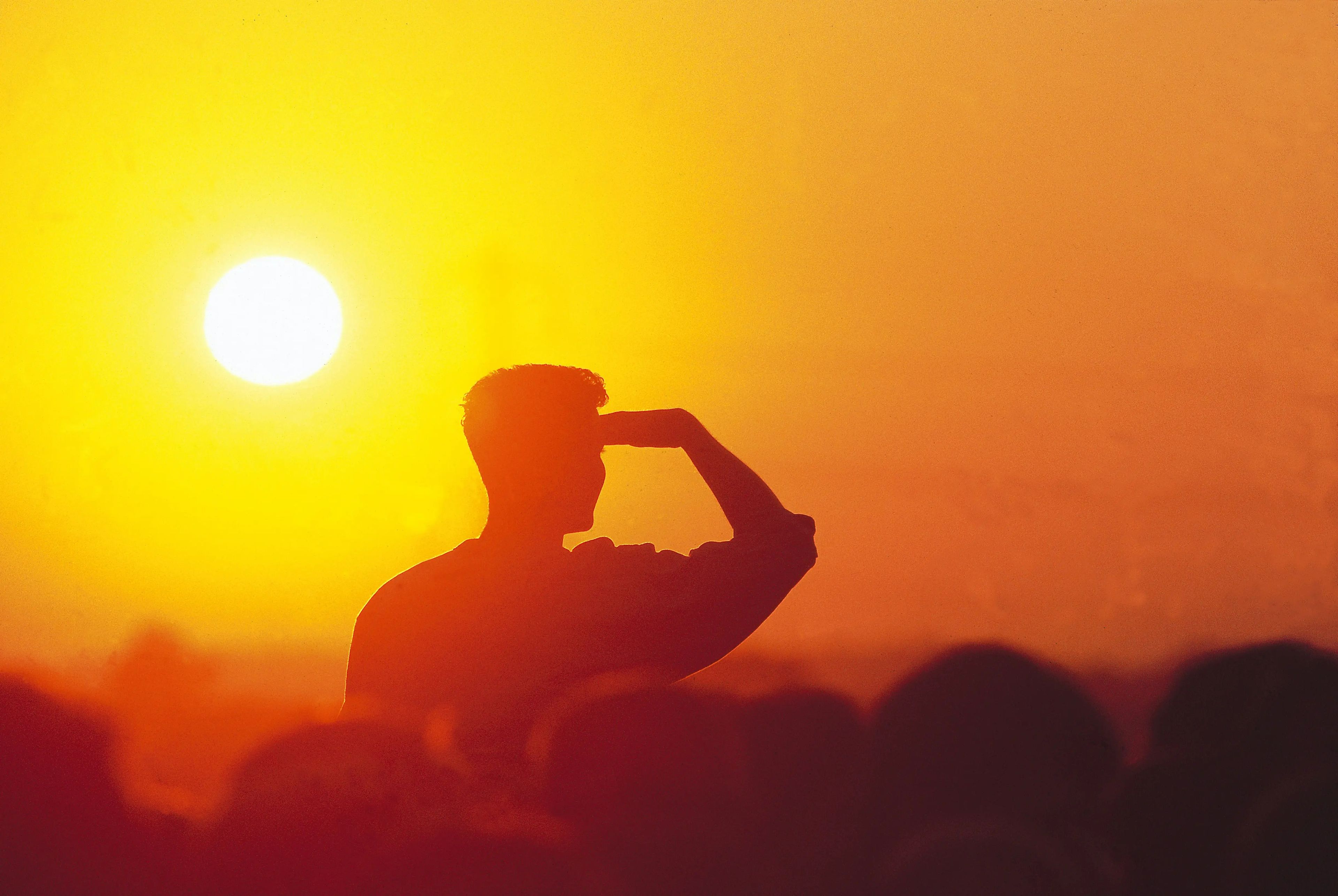 Un aficionado se protege los ojos durante la puesta de sol en el Festival de Glastonbury, en el Reino Unido.