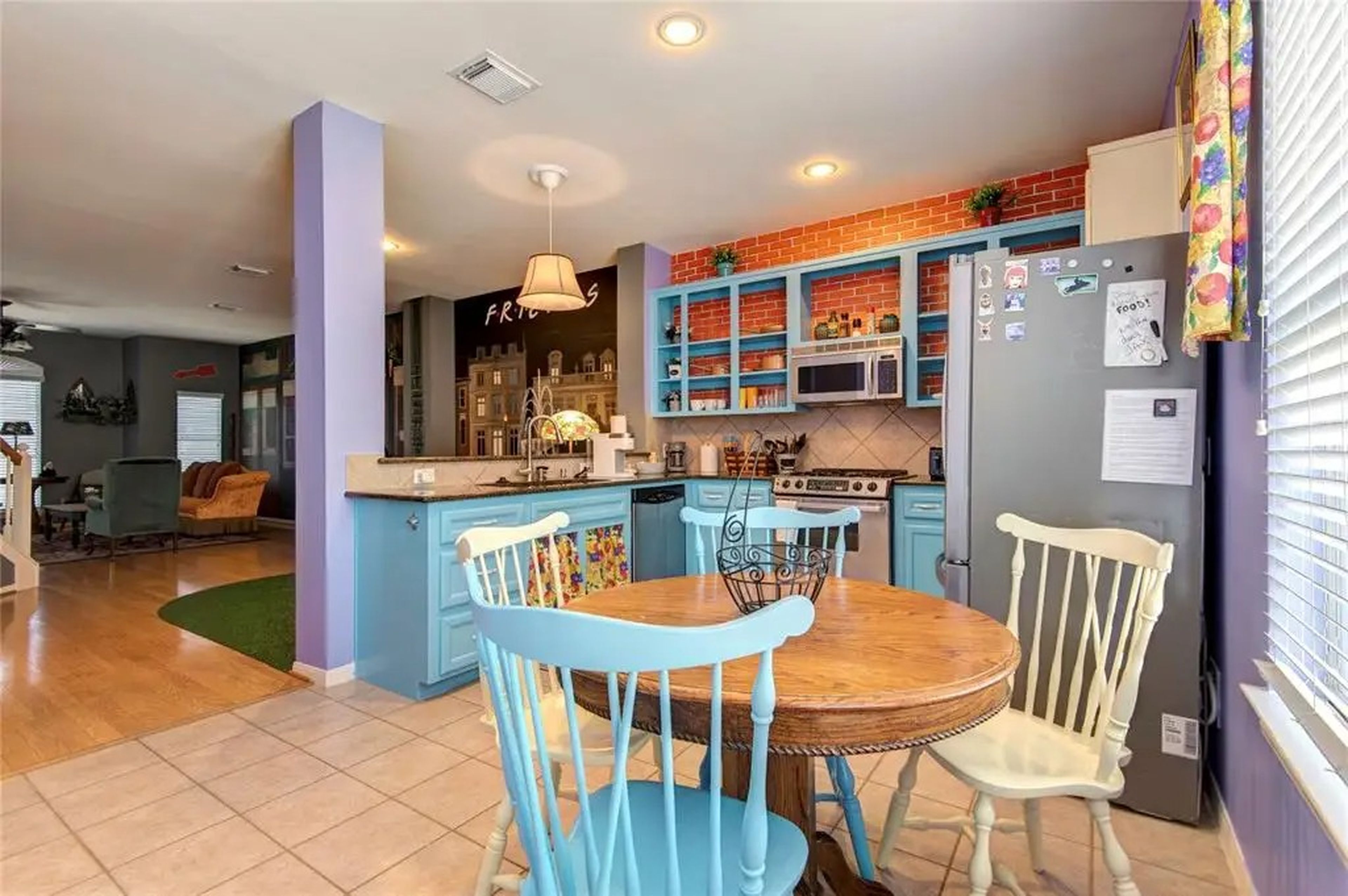 Hay una clásica mesa de desayuno, sillas de distintos colores y paredes moradas, igual que en el apartamento de Mónica.