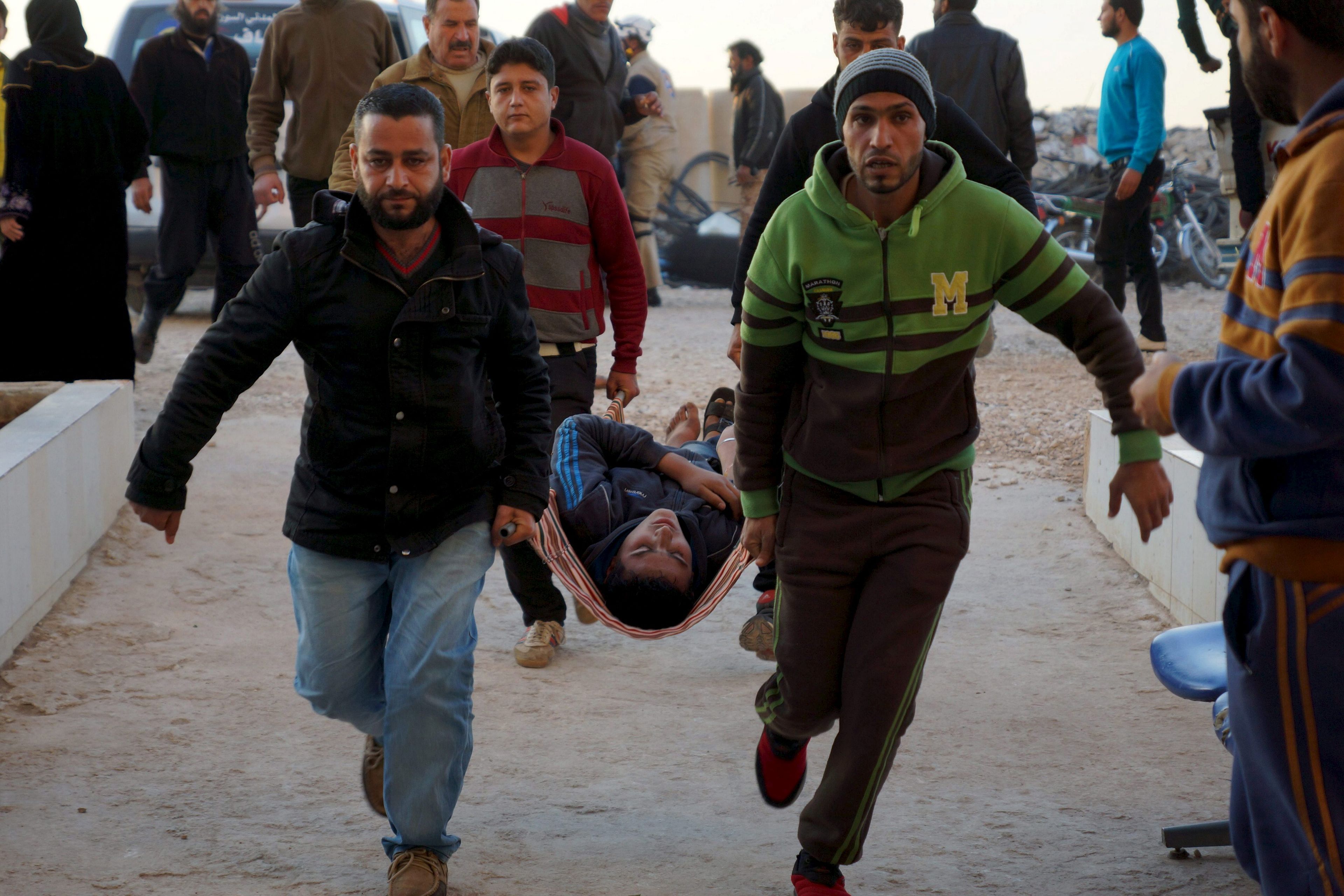 Imagen de 2015 de la guerra en Siria: 2 hombres transportan a una persona herida.