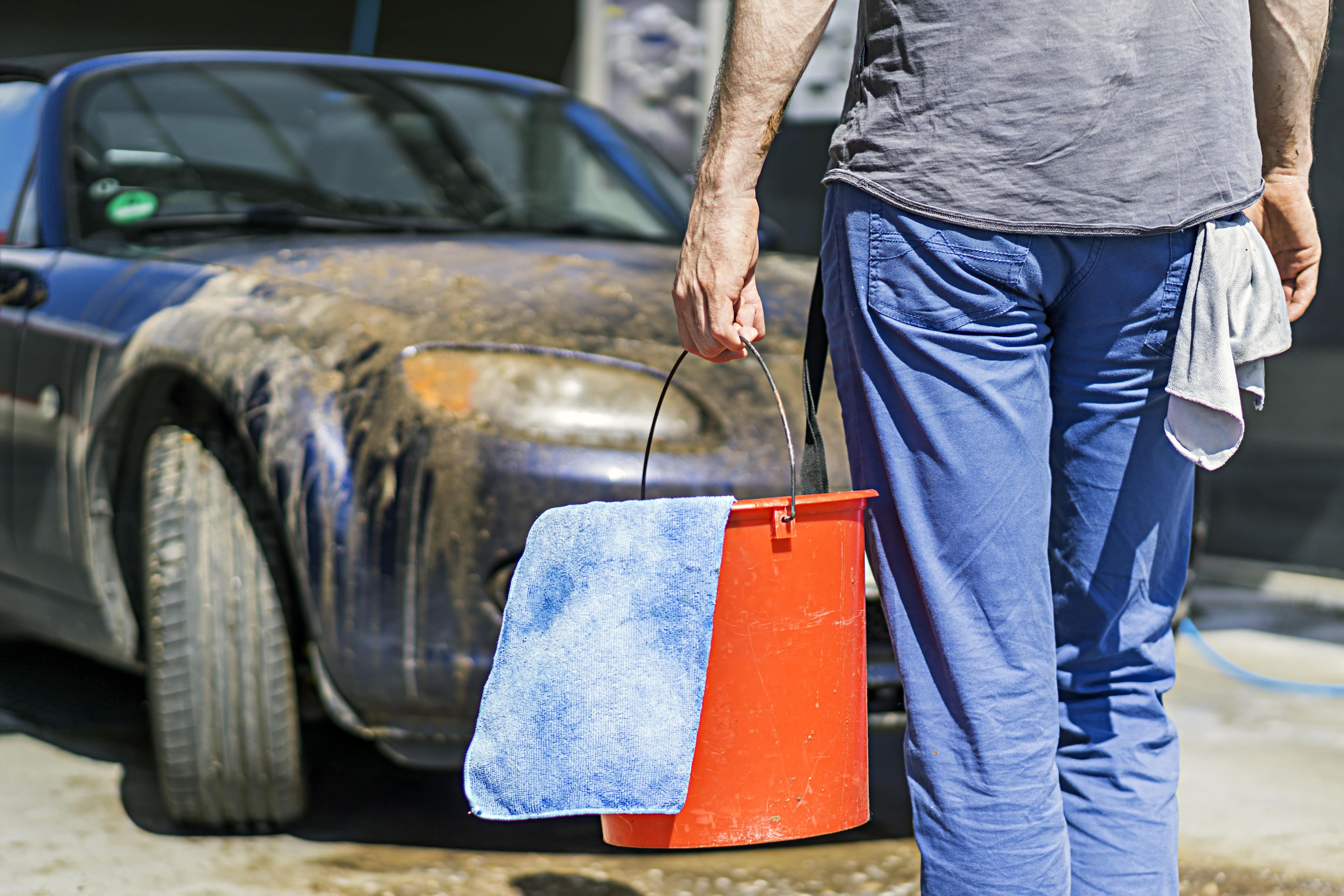 Un hombre se dispone a limpiar su coche lleno de polvo