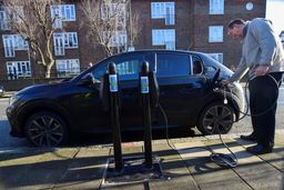 Un hombre recargando un coche eléctrico