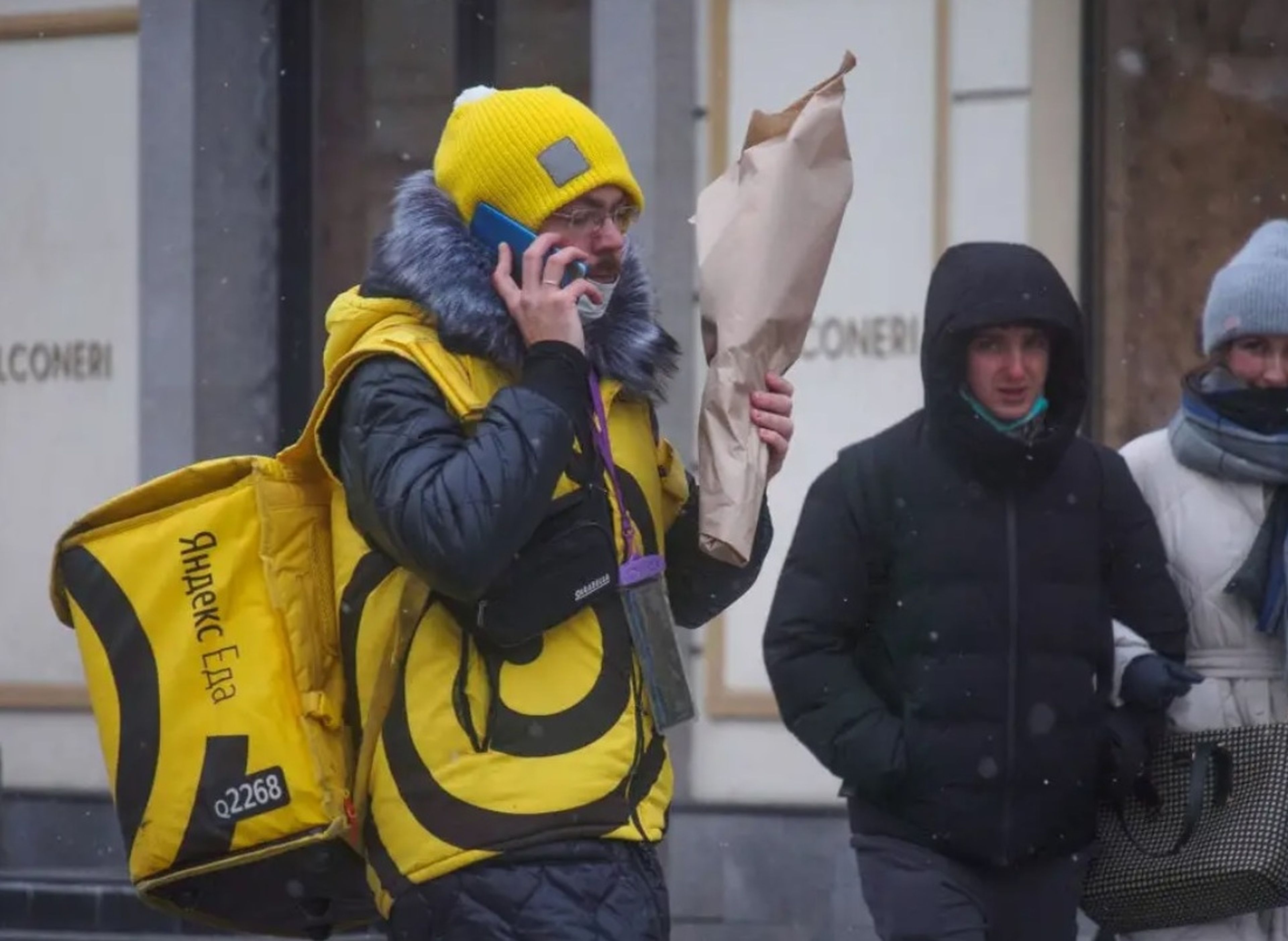 Un mensajero de Yandex para la entrega de alimentos se pasea por Moscú con un ramo de flores a principios de marzo.