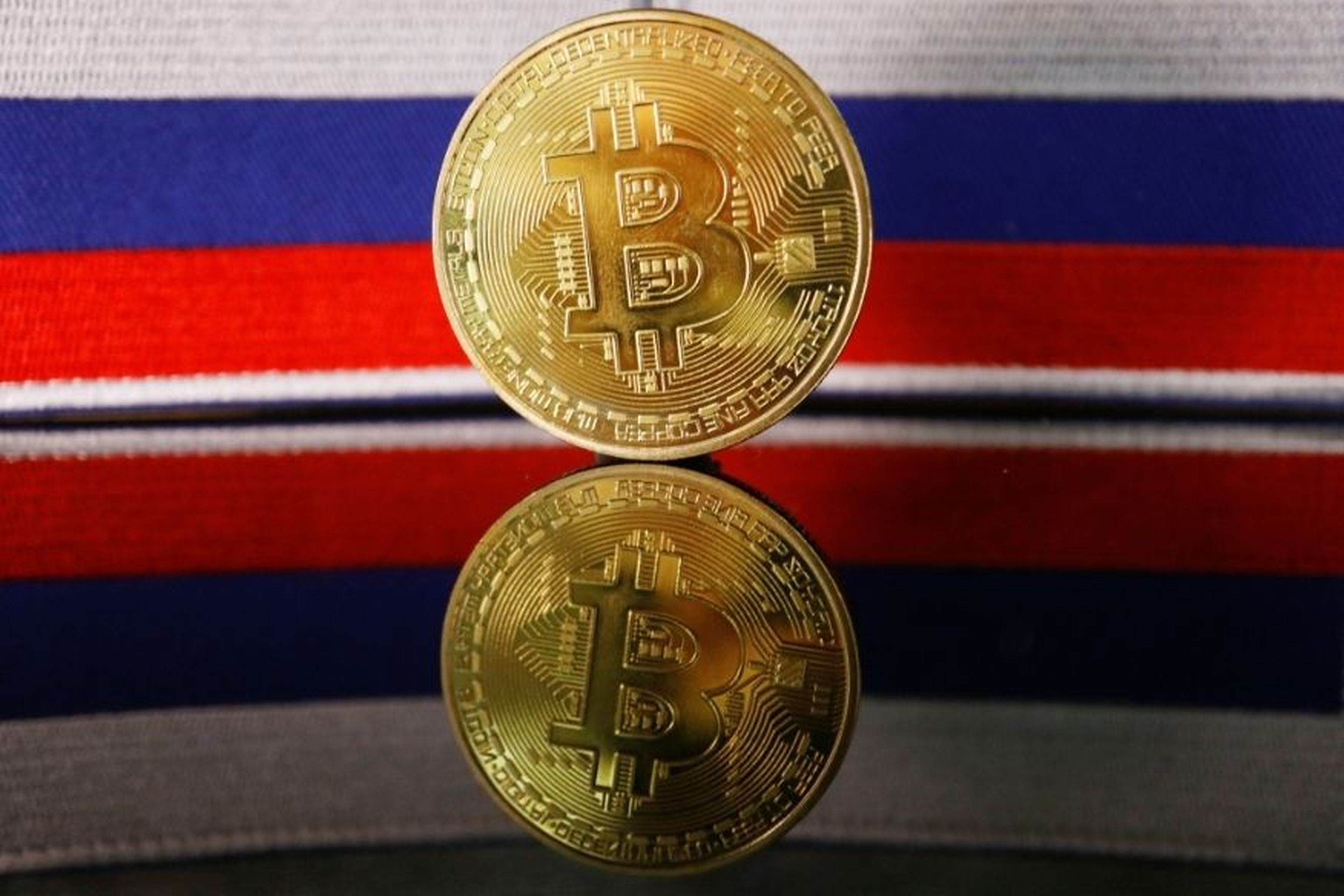 Una moneda de bitcoin delante de la bandera de Rusia.