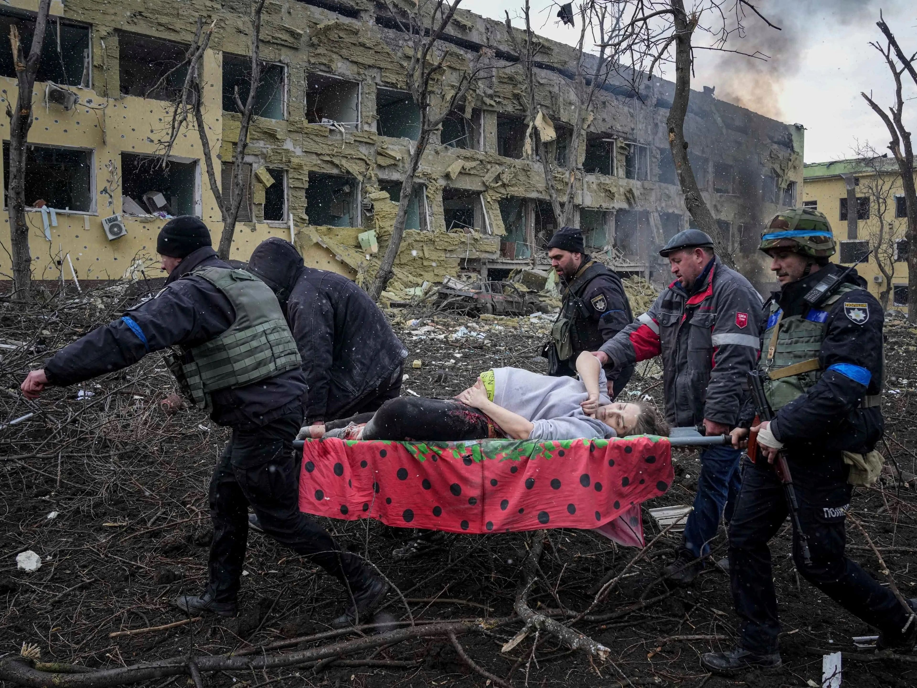 Empleados y voluntarios de emergencias ucranianos llevan a una mujer embarazada herida desde un hospital de maternidad que fue dañado por los bombardeos en Mariúpol, Ucrania, el 9 de marzo de 2022.