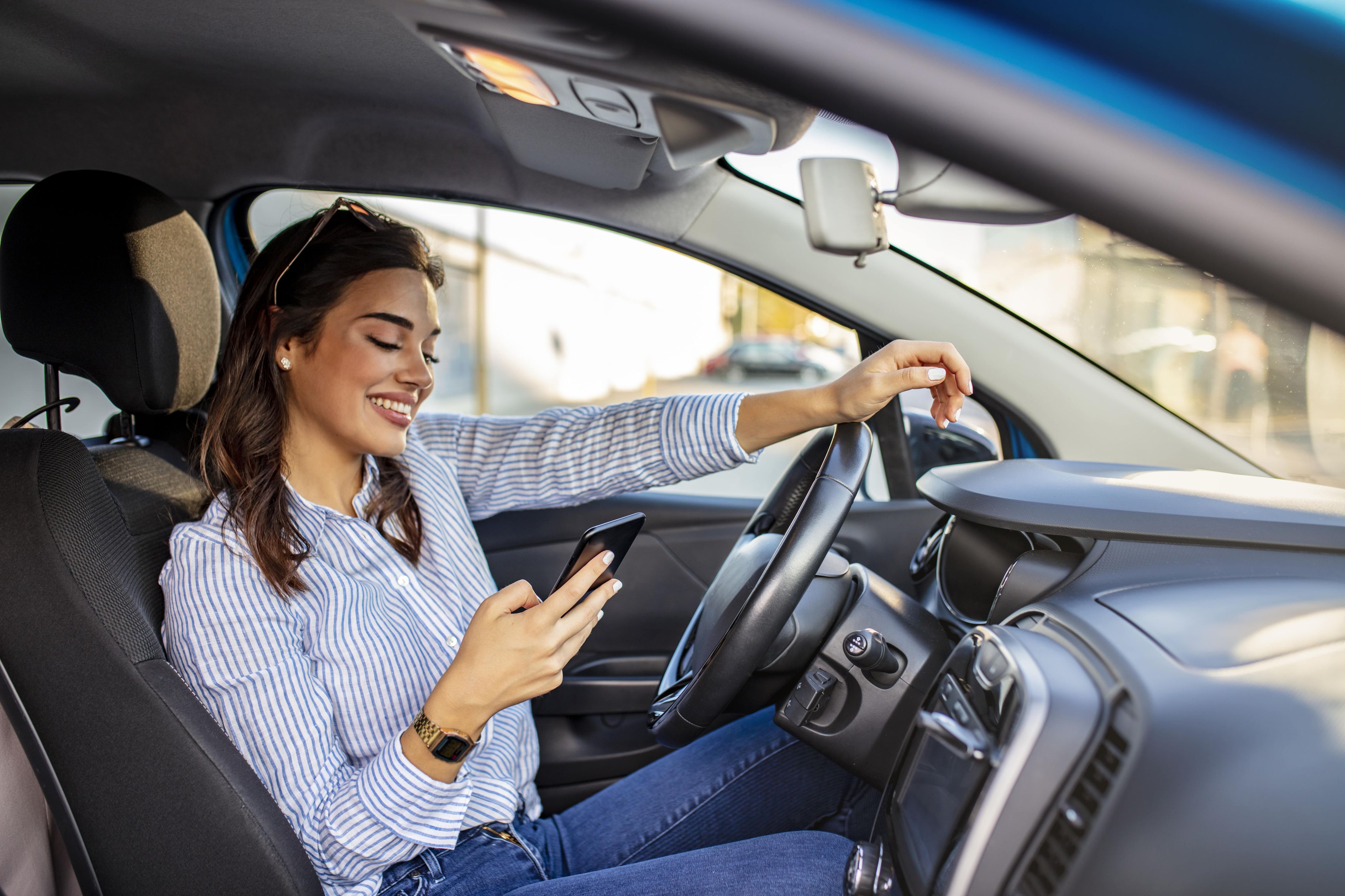 Una mujer mira el móvil mientras conduce