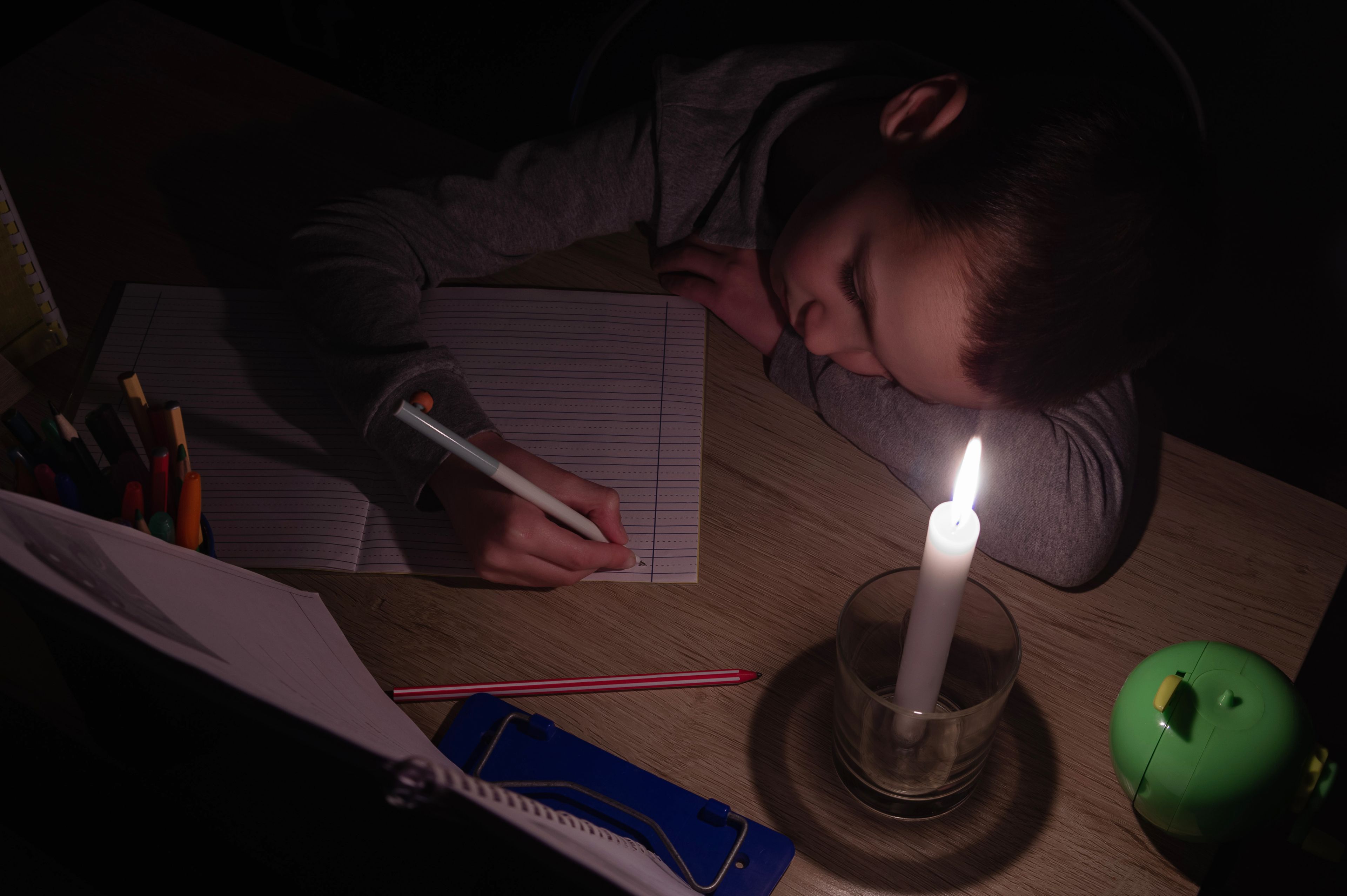 Un niño estudia a la luz de una vela.