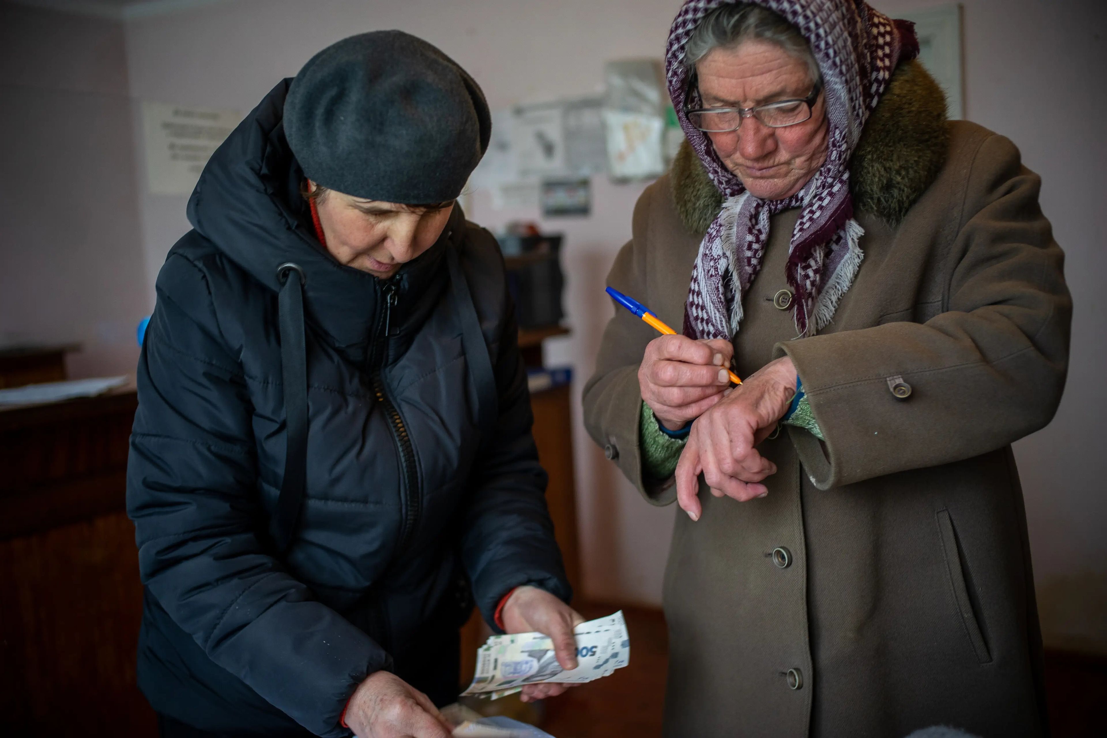 Olga Hrushetska cuenta el pago de la pensión de Stefa Viyents, una trabajadora sanitaria jubilada de 71 años.