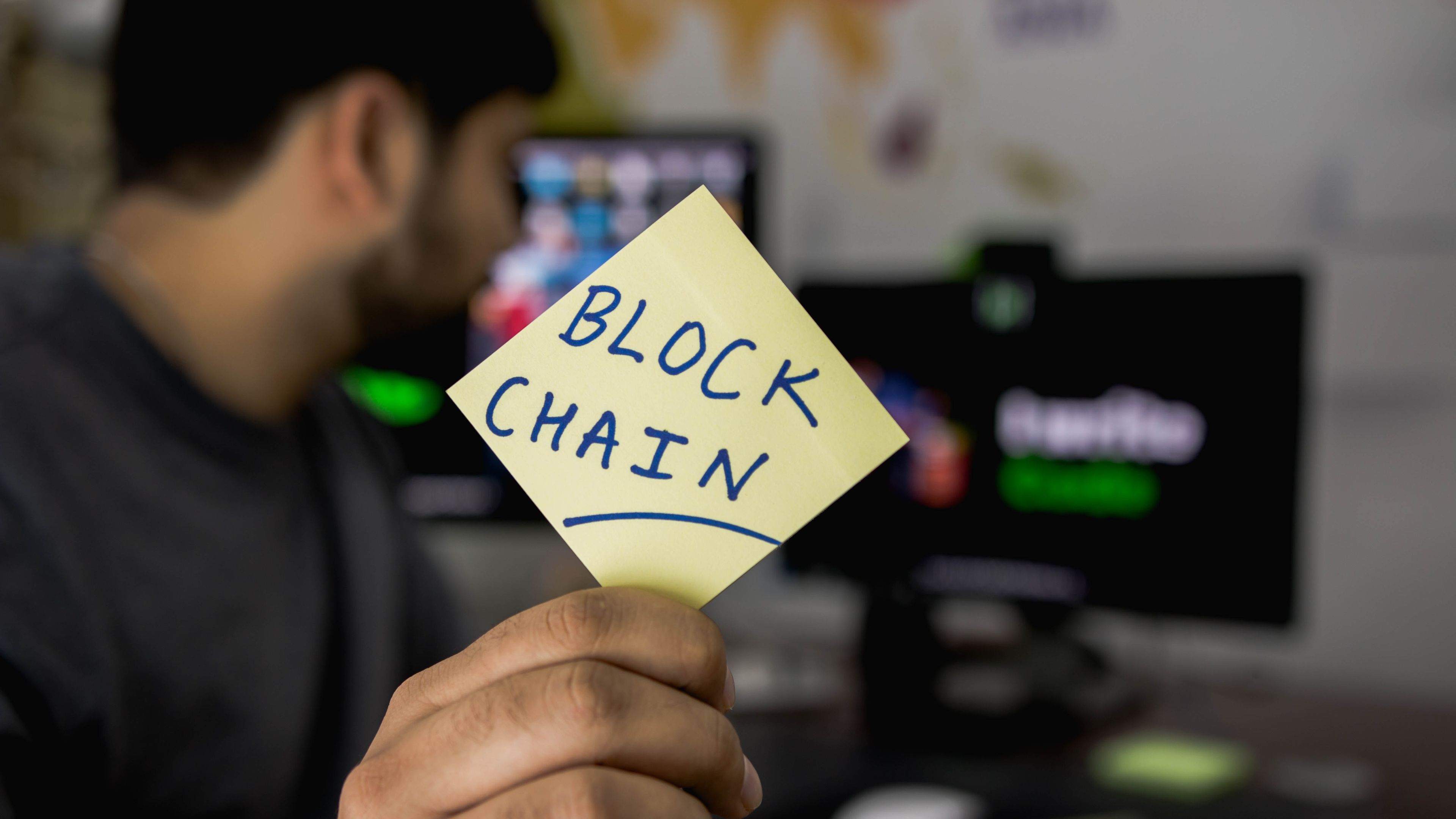 Una persona sujeta un post-it en el que se ha escrito 'blockchain'.