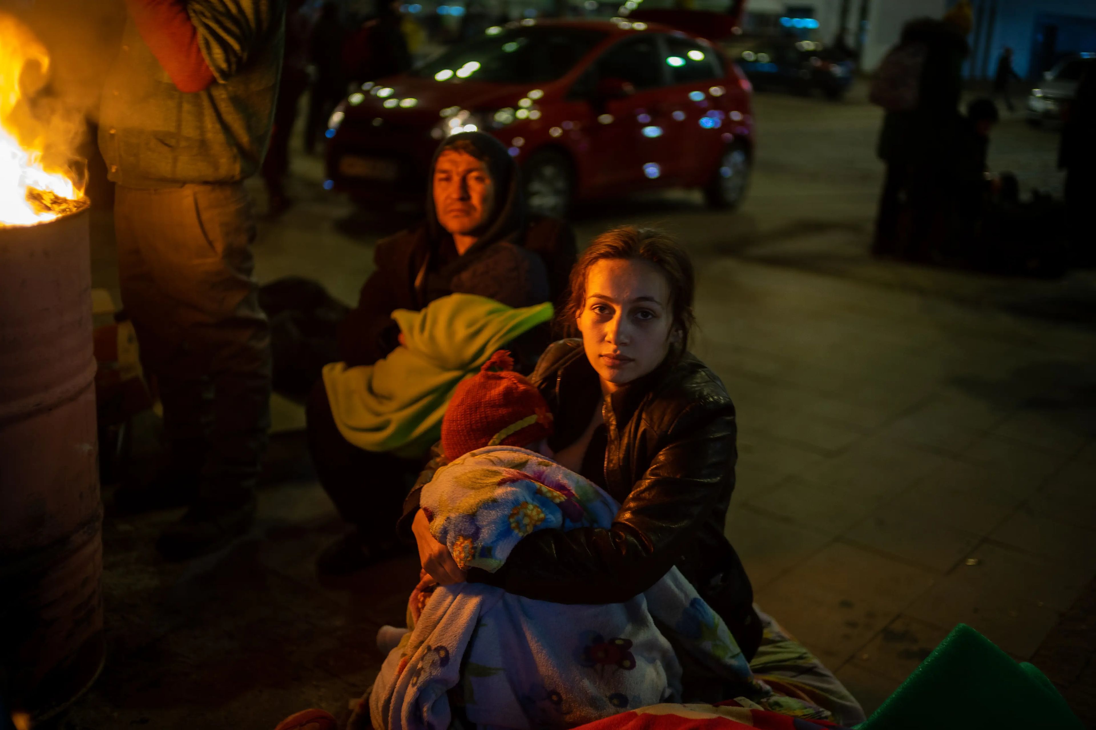 Un grupo de personas enciende una fogata en la estación de tren de Leopólis para sobrellevar las bajas temperaturas mientras esperan a poder subirse a un tren que les saque de Ucrania.