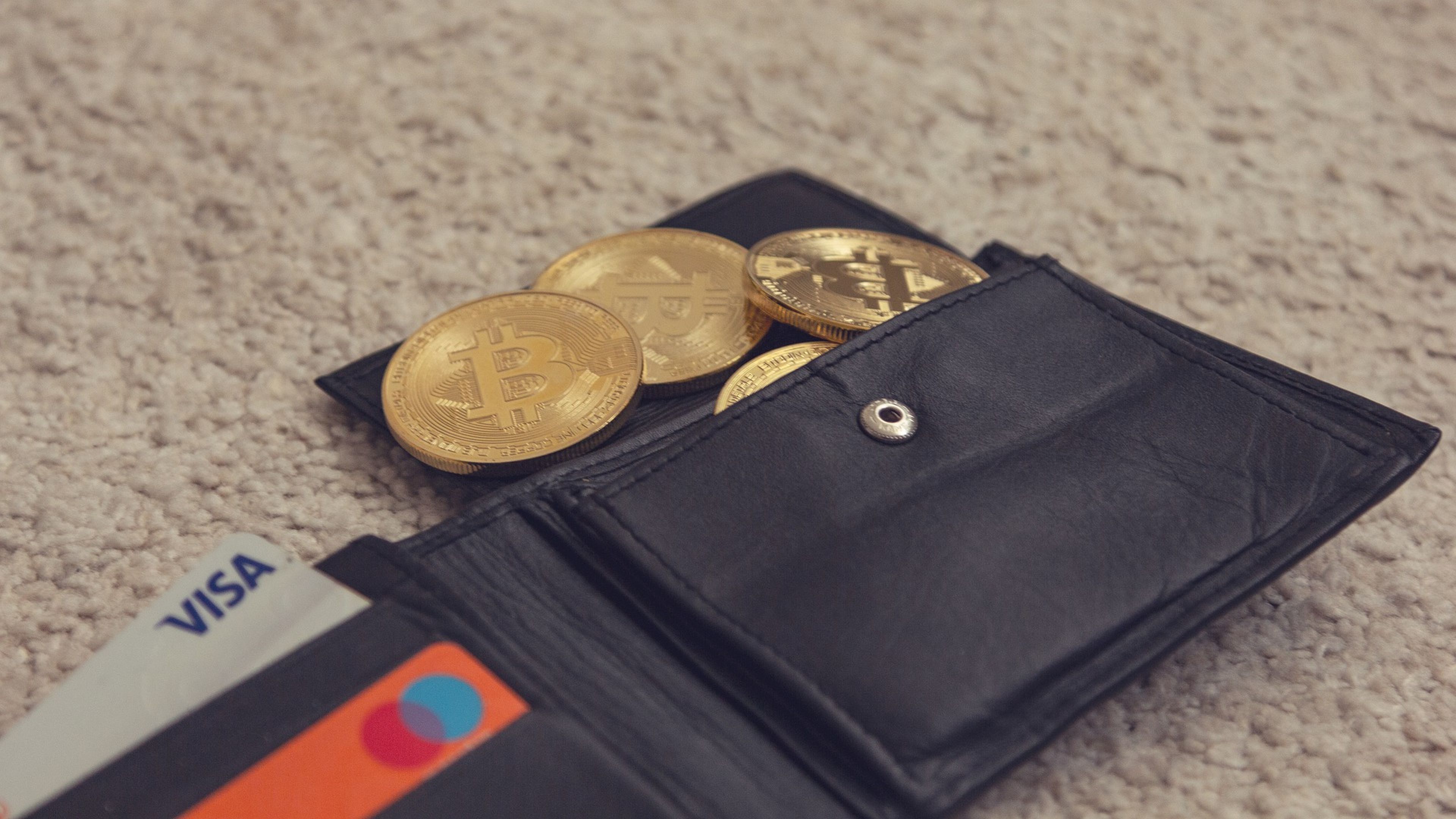 Una cartera con una tarjeta de crédito y varias criptomonedas.