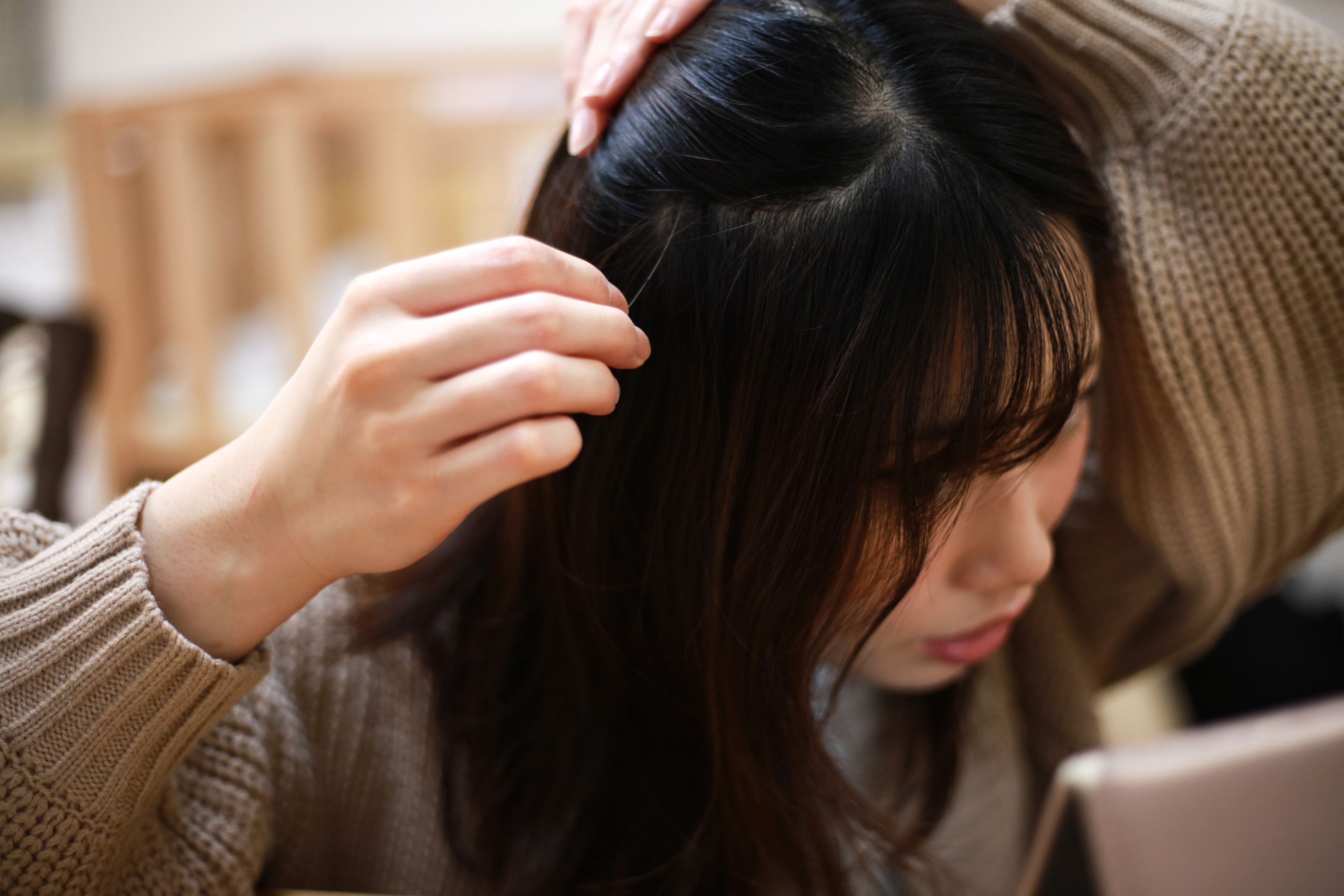 Chica joven arrancándose una cana del pelo