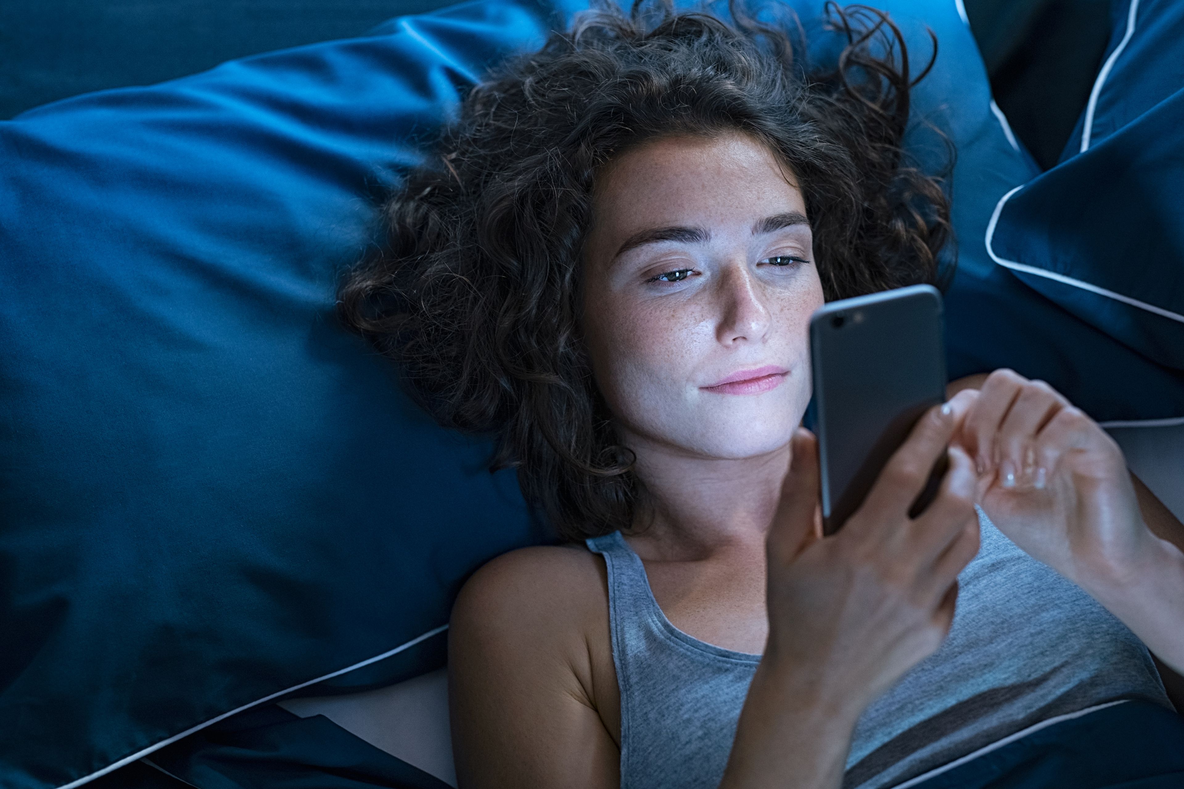 Chica usando el móvil en la cama