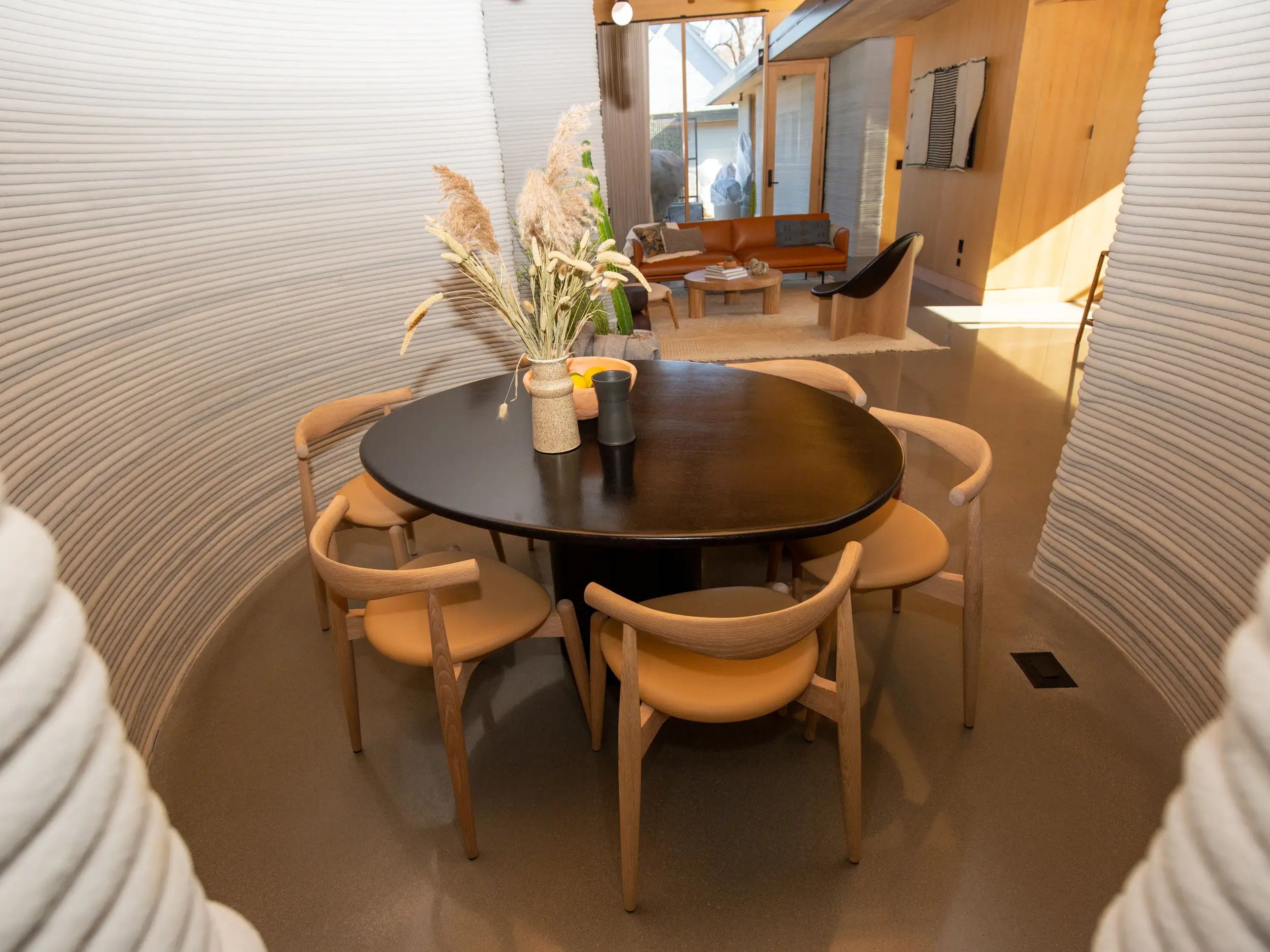 A dining table surrounded by curving 3D printed walls.