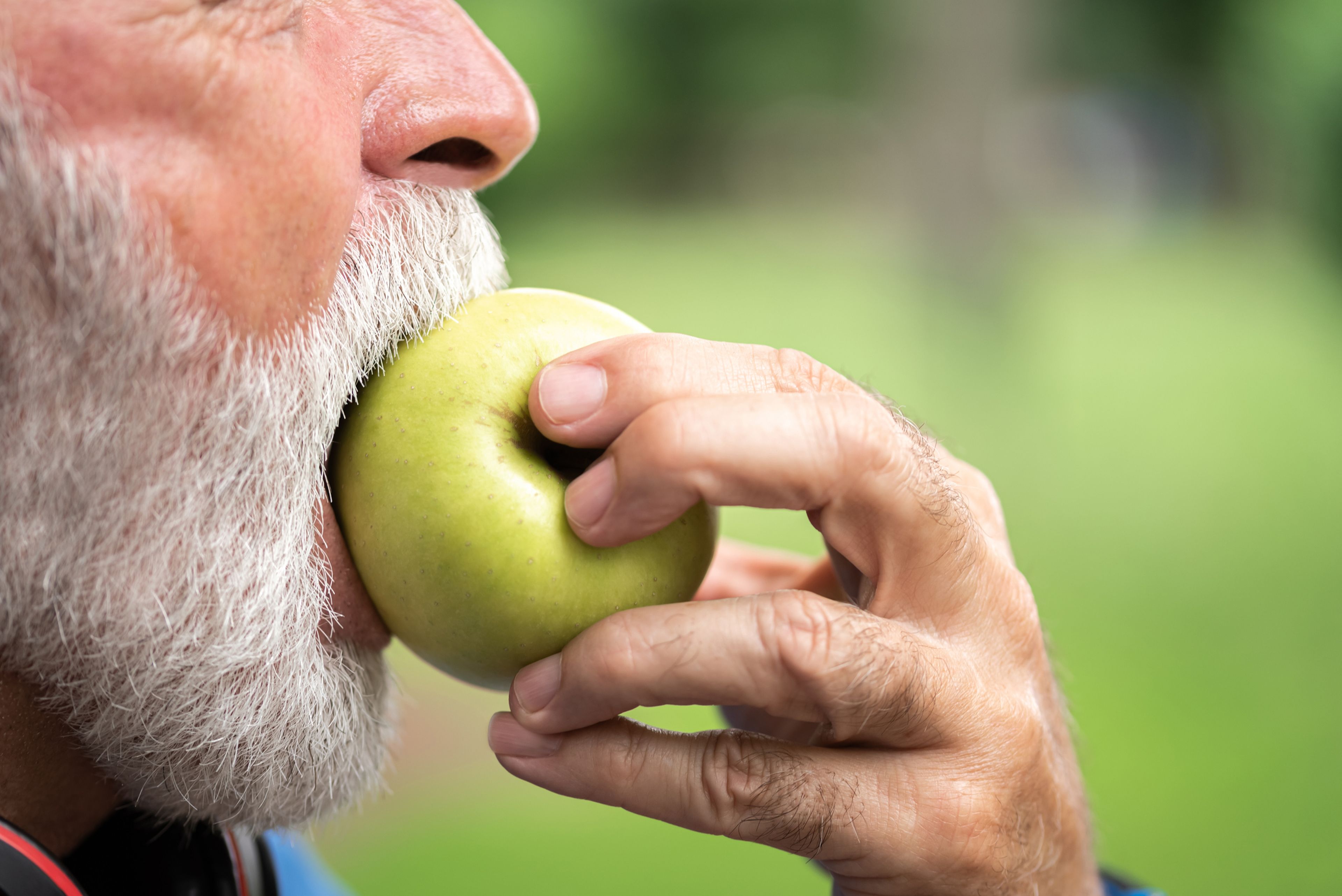 Hombre comiendo una manzana verde