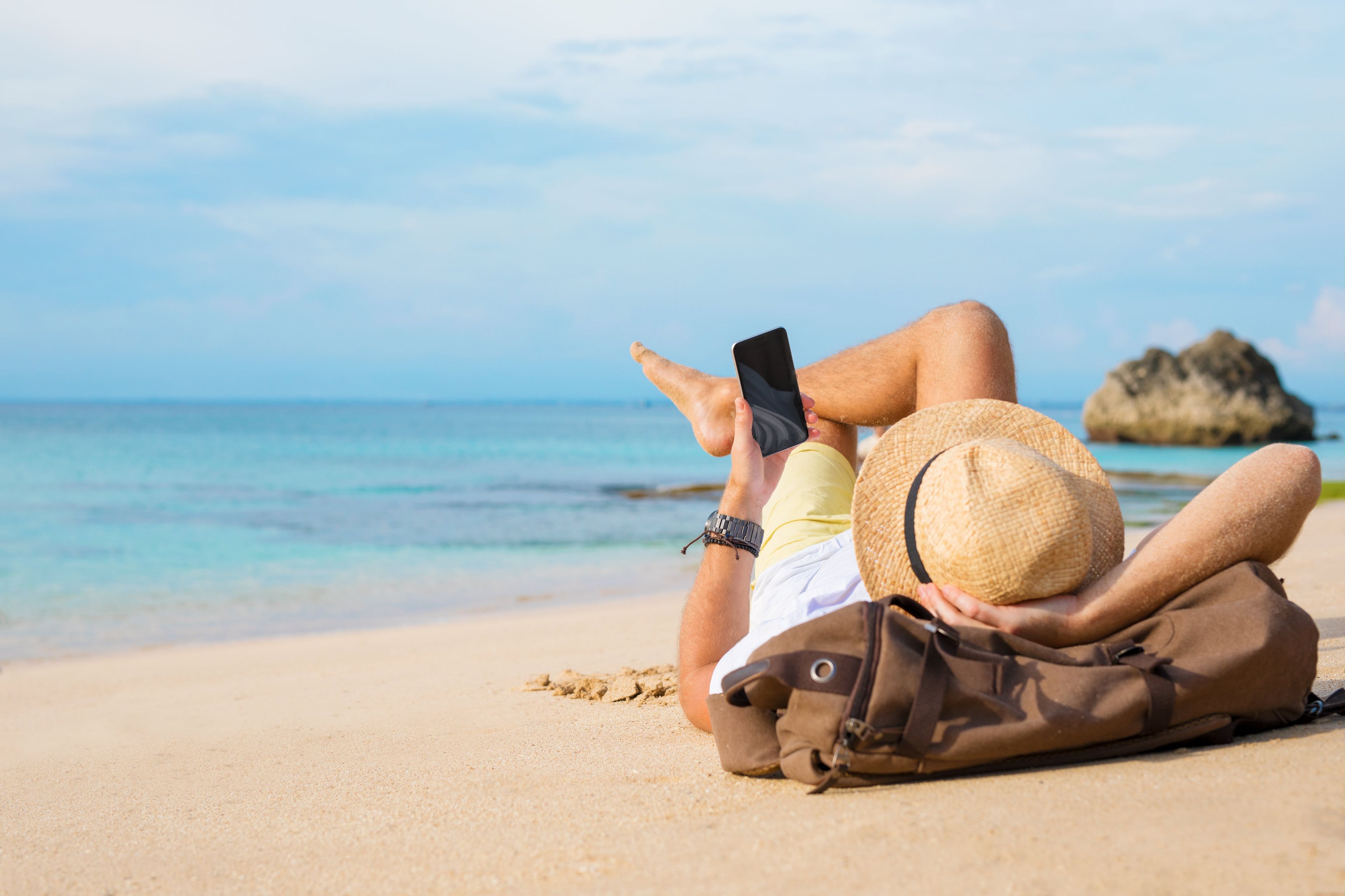 Un hombre consulta el móvil en la playa