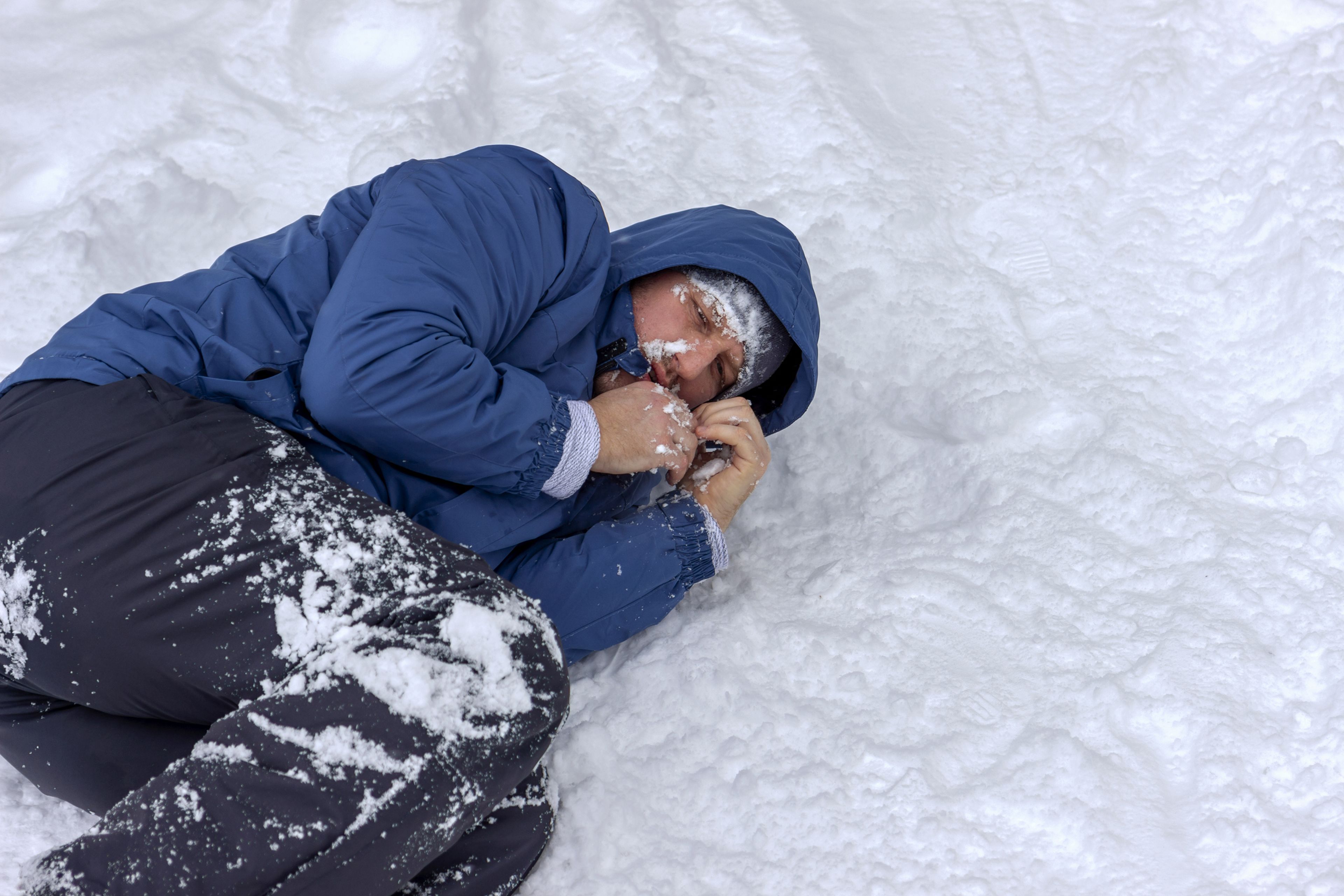 Hombre tumbado en la nieve con hipotermia