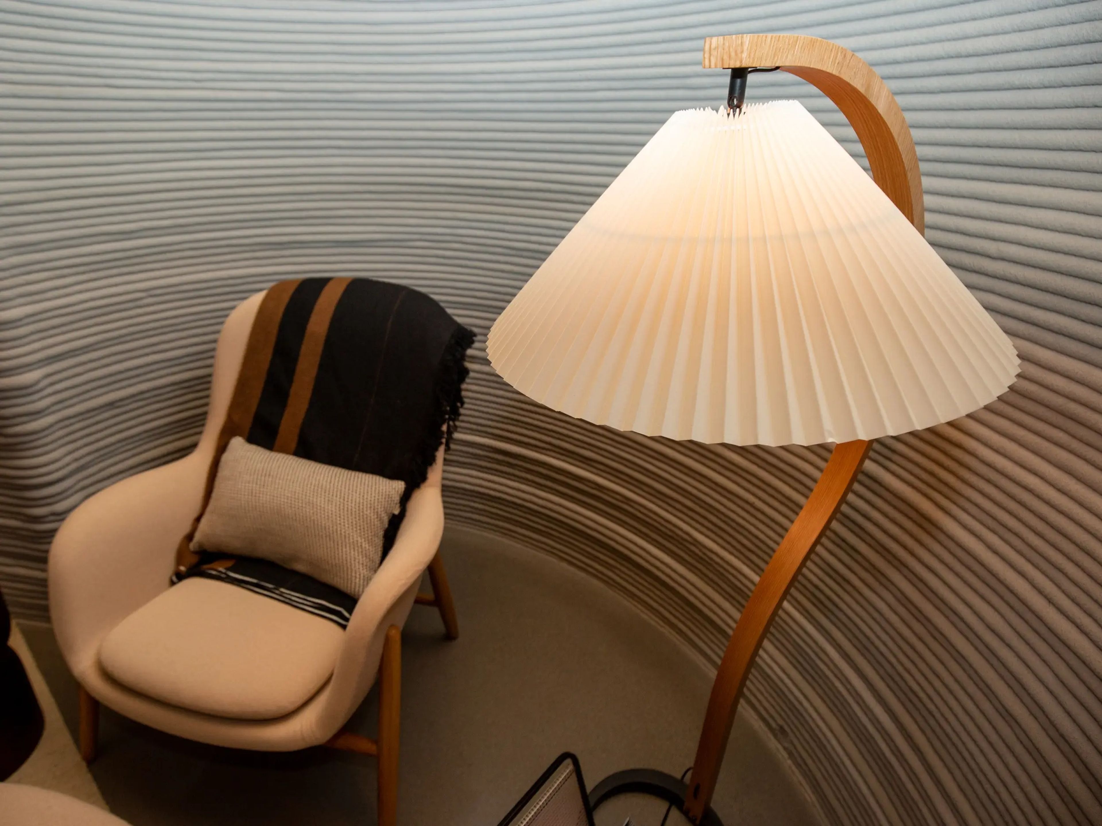 A lounge chair and light fixture in front of a 3D printed wall.