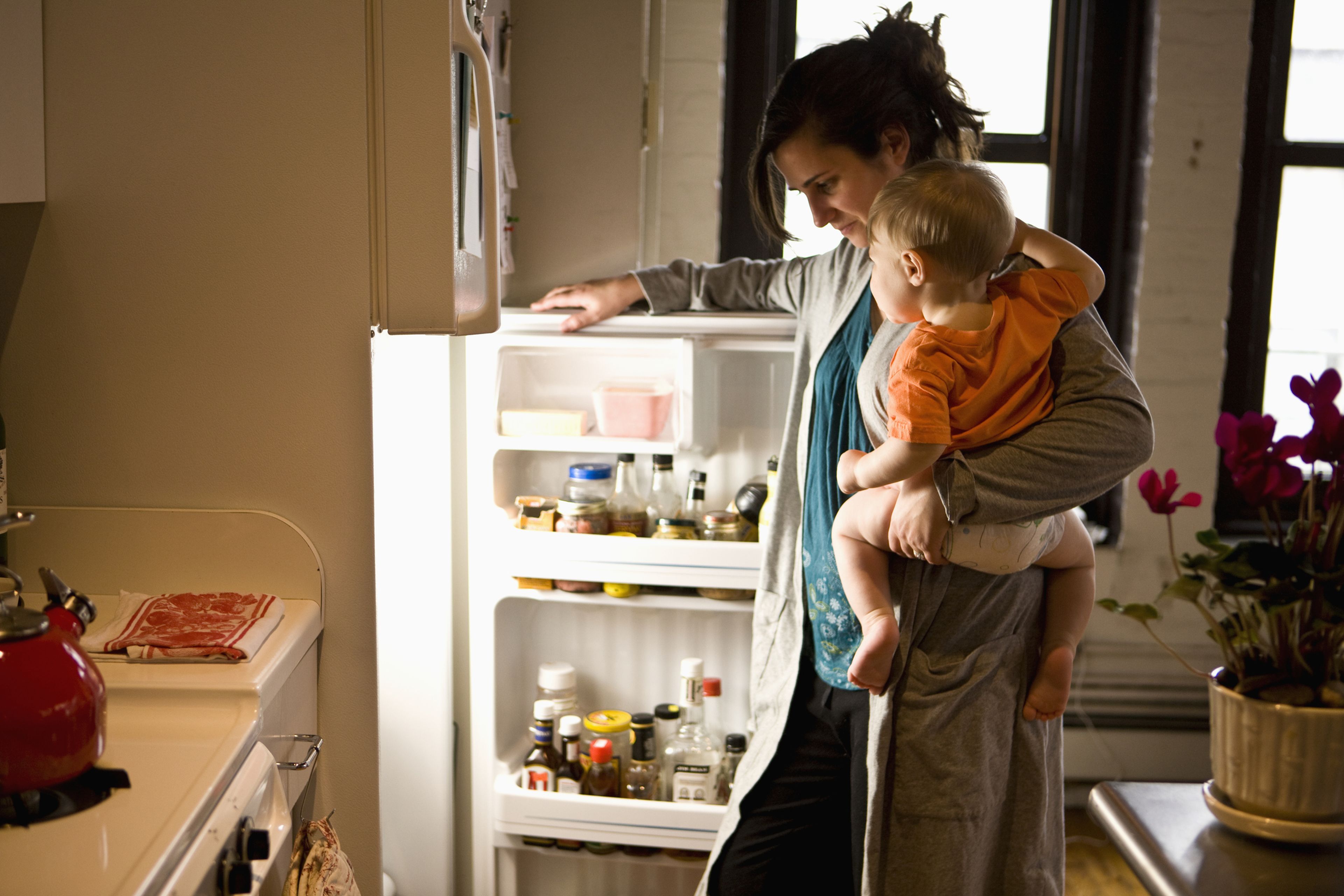 Una mujer abre el frigorífico con un bebé encima.