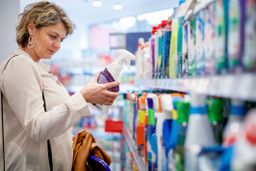 Mujer comparando productos mientras hace la compra en el supermercado
