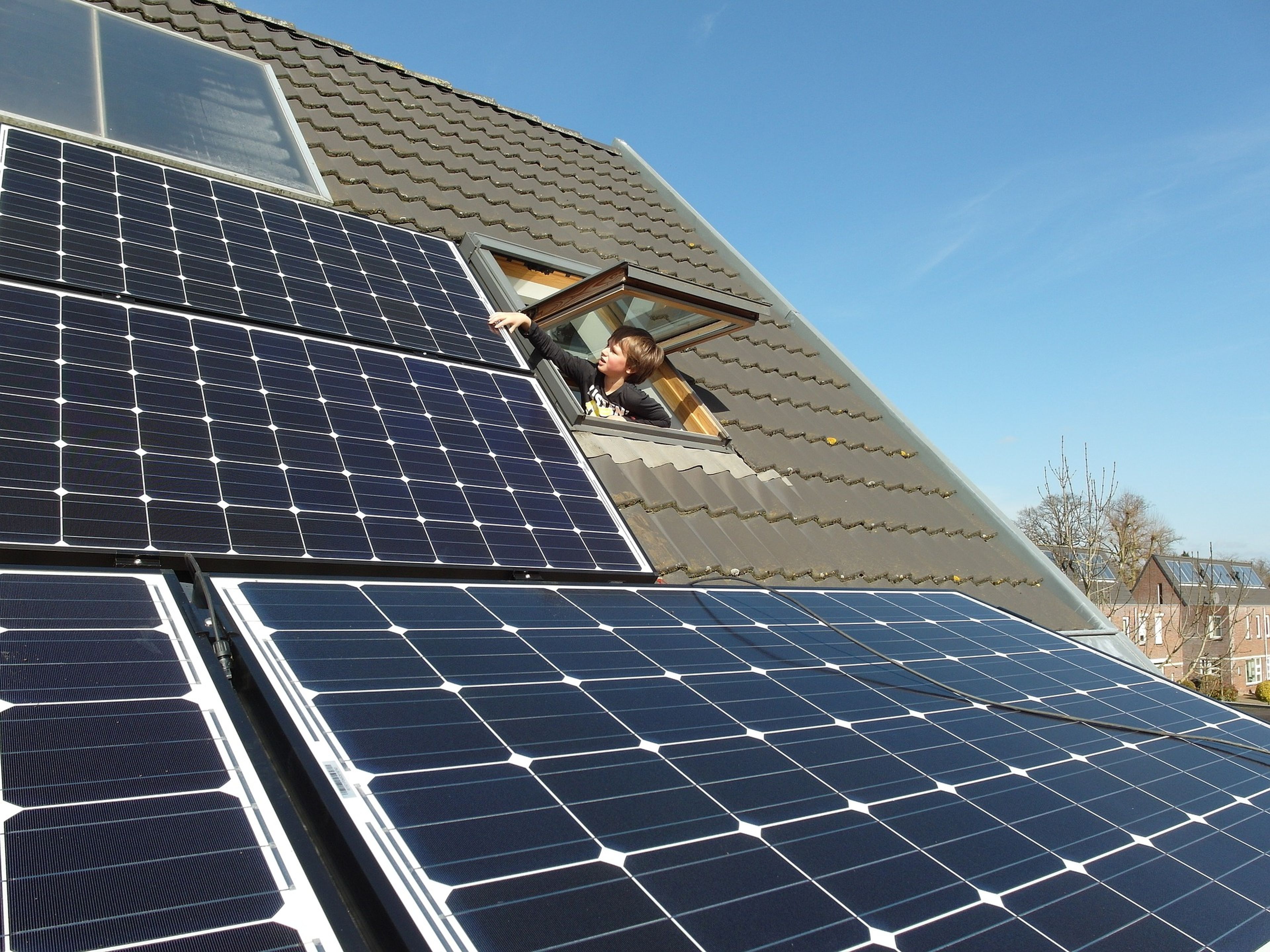 Un niño toca unas placas solares en el tejado.