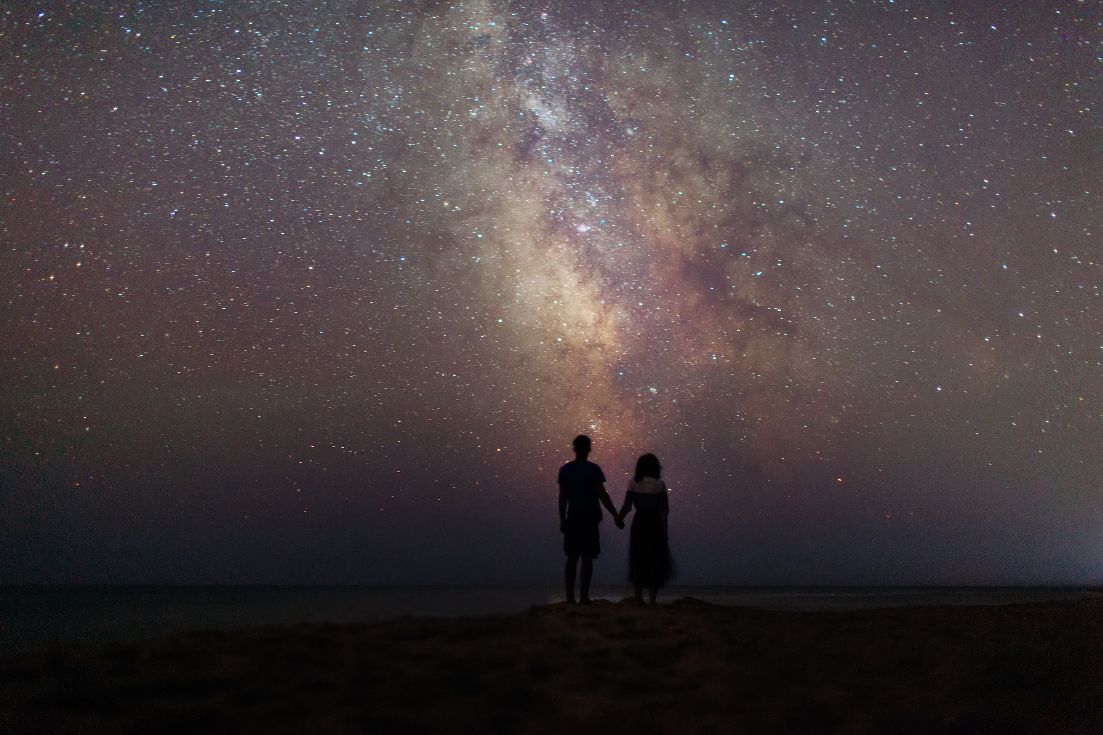 Una pareja mira de noche al cielo con estrellas