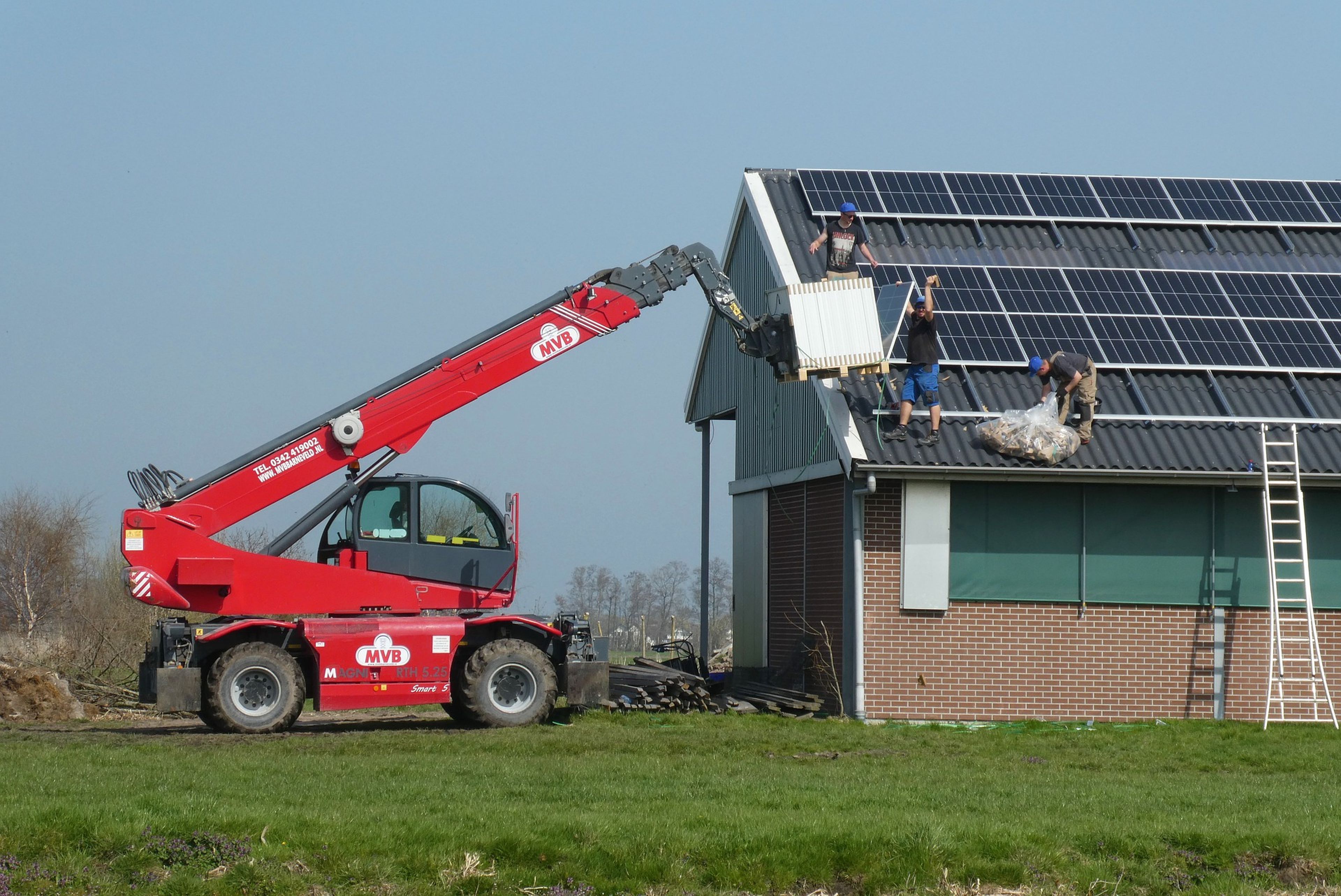 Varias personas instalan paneles solares en un tejado.