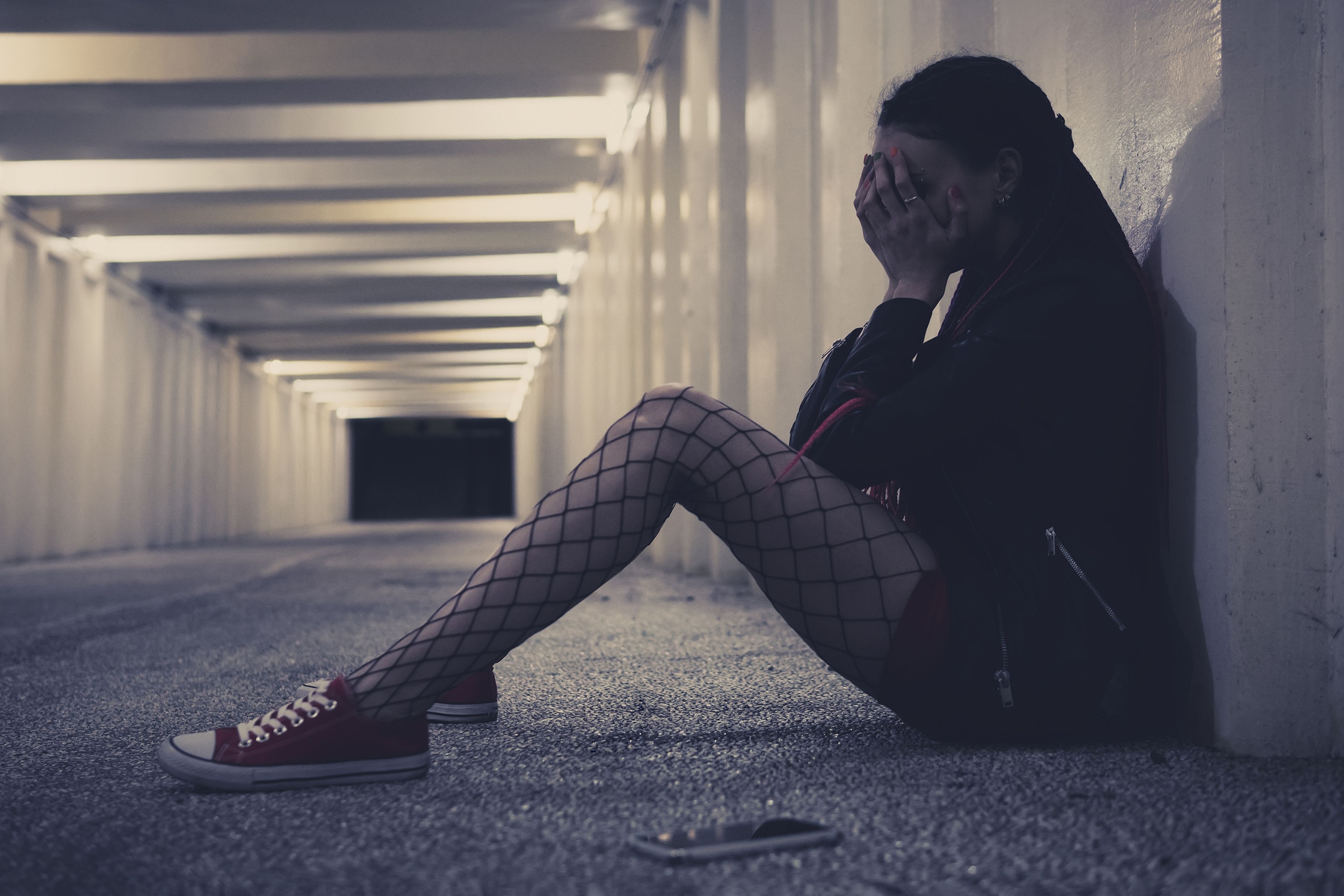 Chica adolescente triste, en el suelo con teléfono