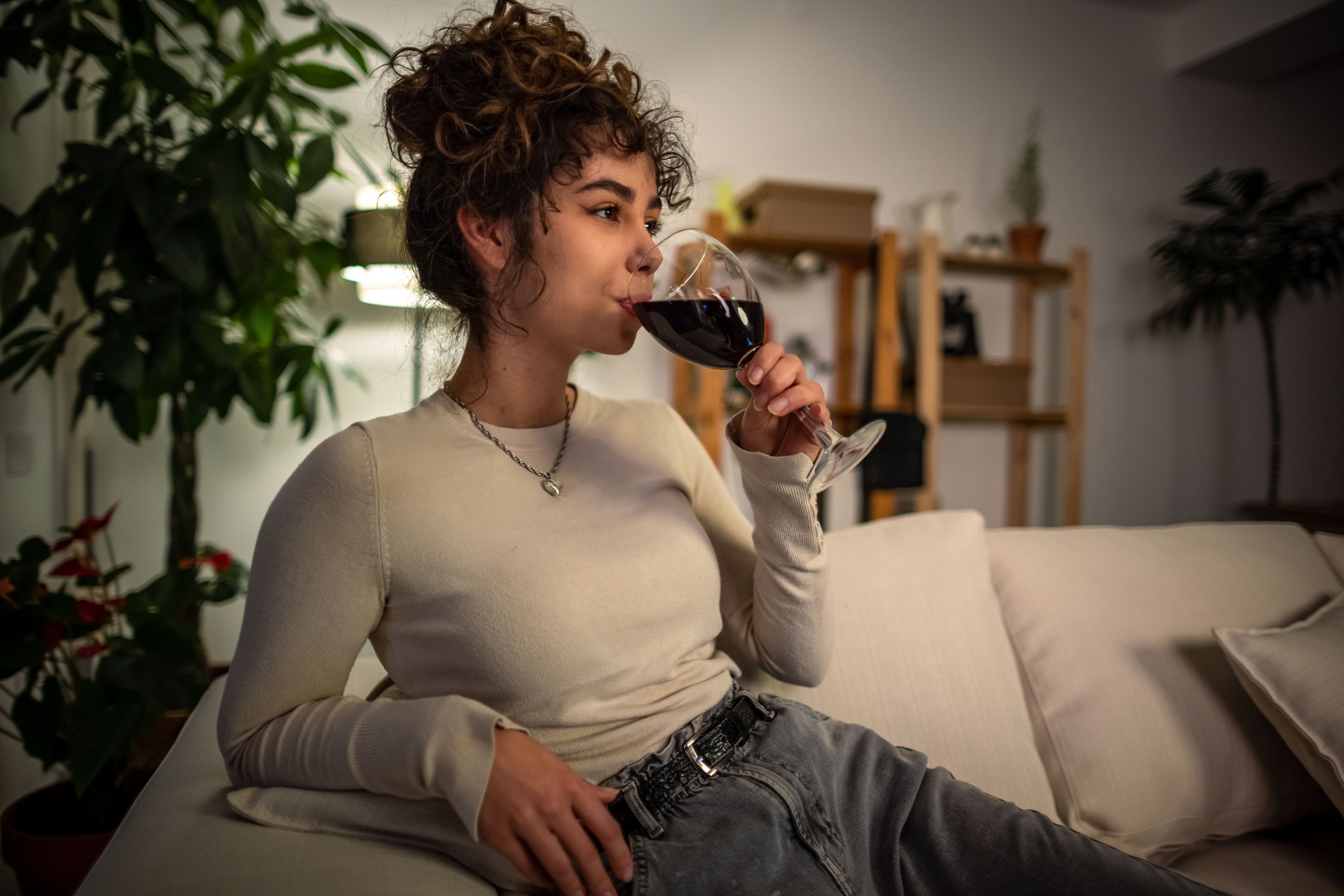 Chica en el sofá bebiendo una copa de vino