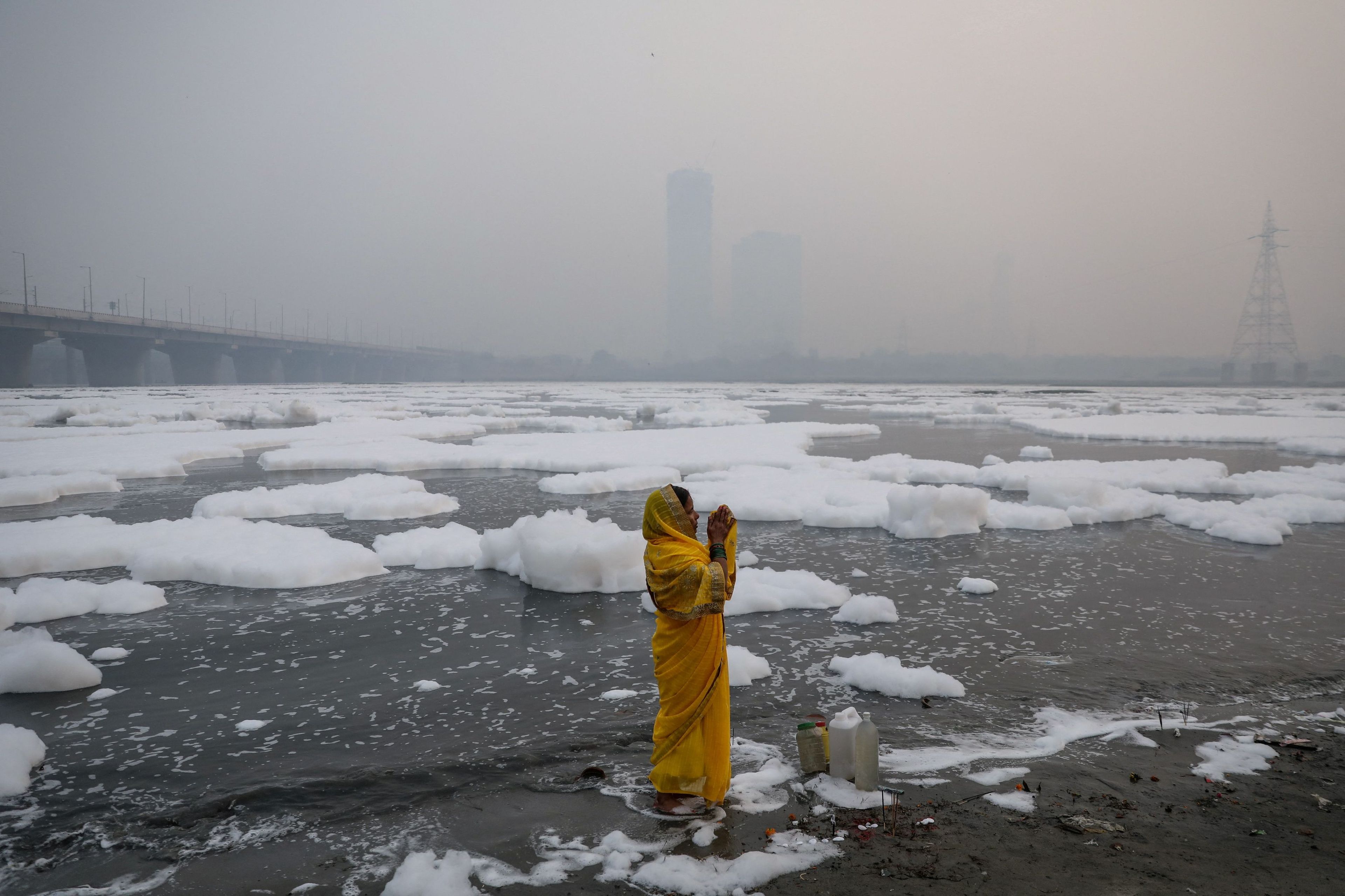 Esta fotografía finalista del Pulitzer muestra a una mujer rezando a orillas del río contaminado Yamuna en una mañana contaminada en Nueva Delhi (India).