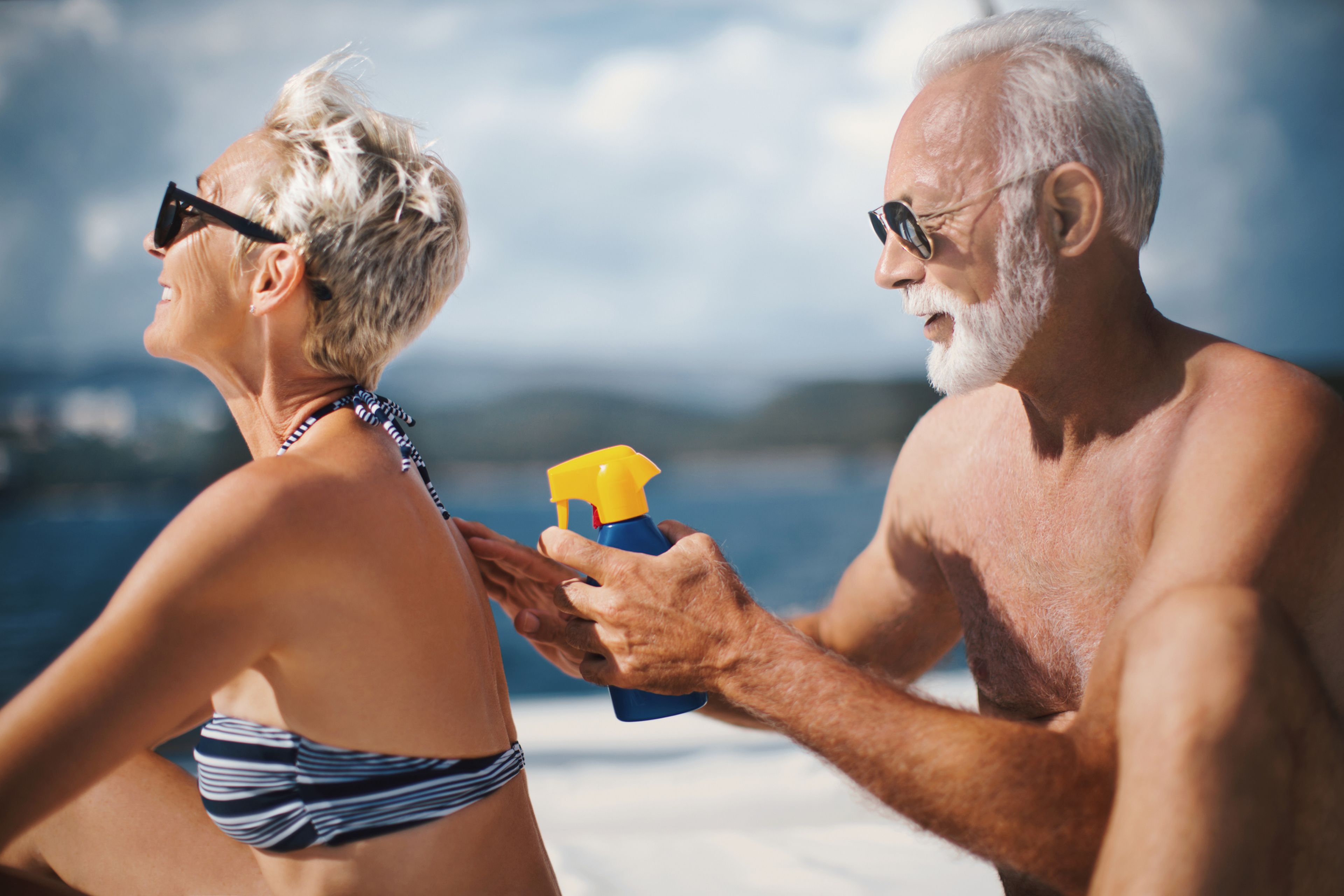 Hombre echando crema solar a su mujer en la playa