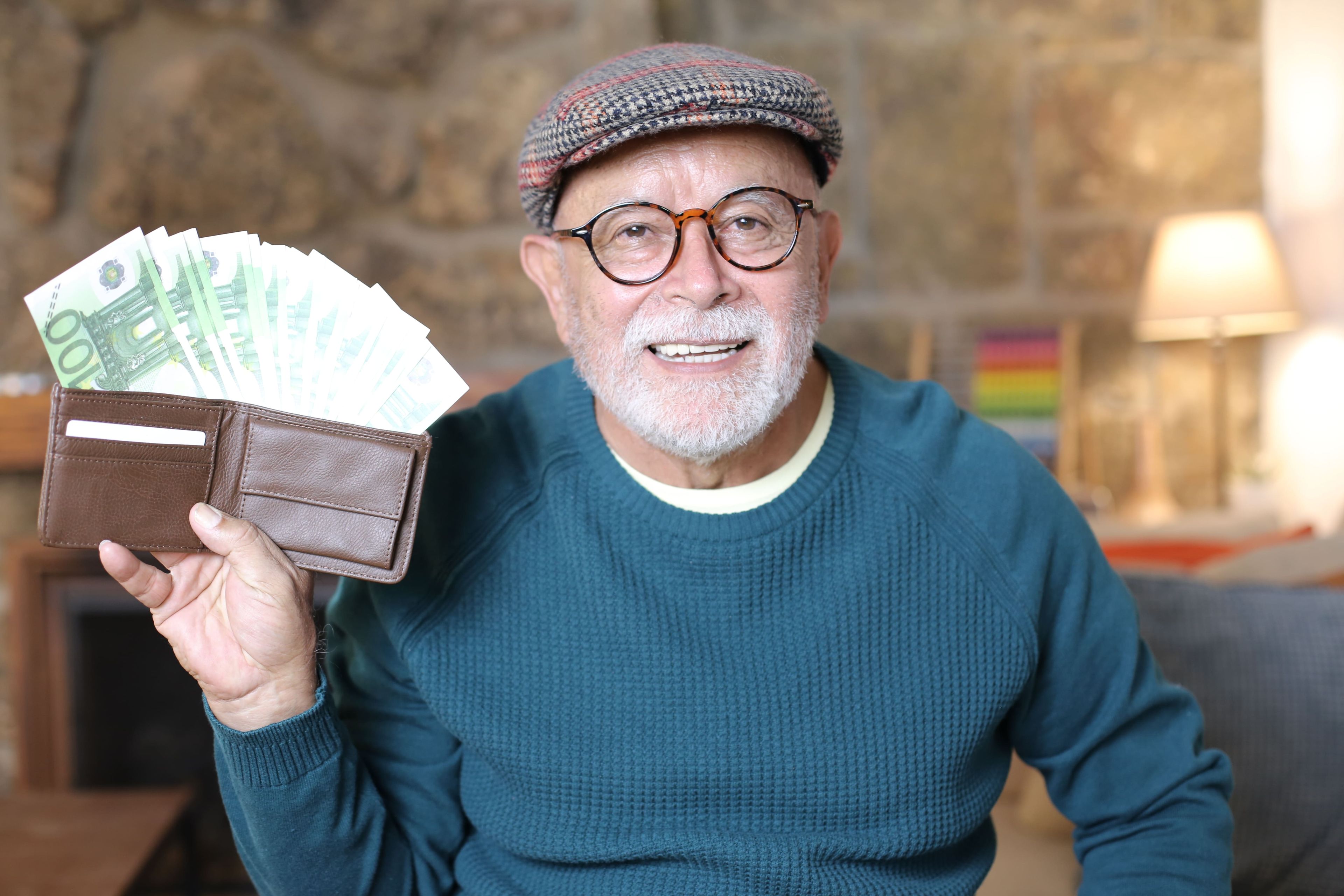 Un hombre mayor enseña billetes de 100 euros
