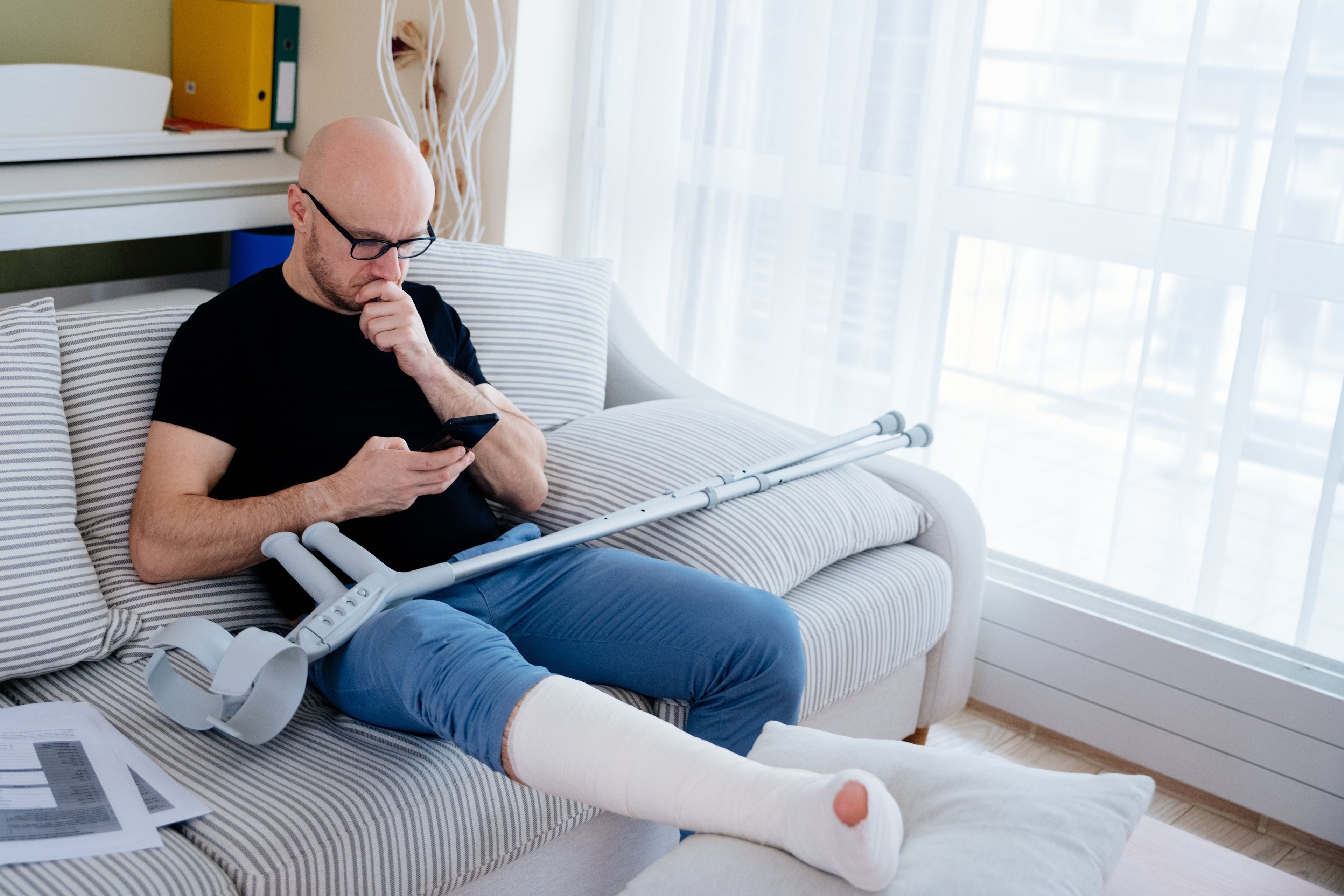 Un hombre con la pierna rota consulta el móvil