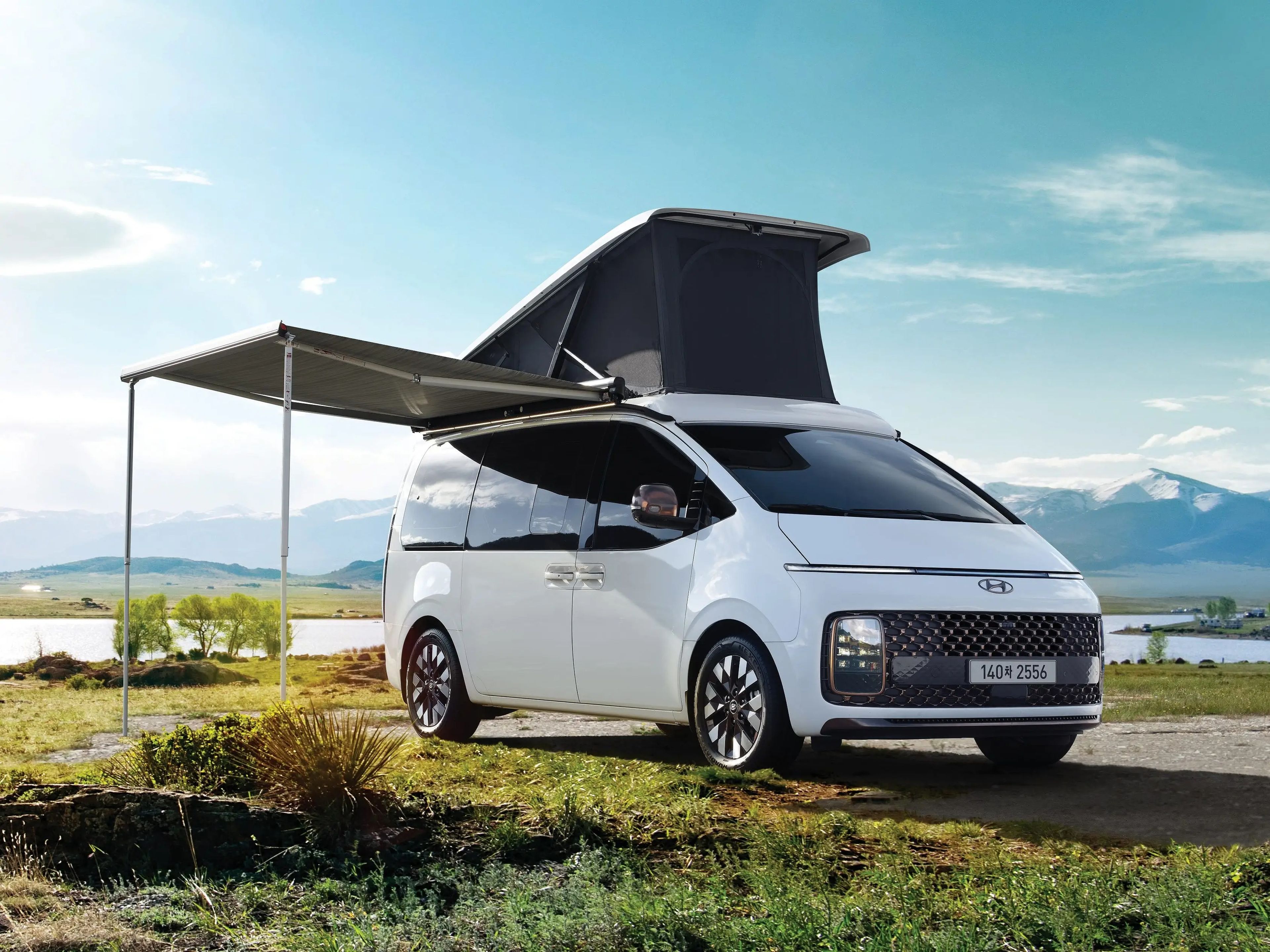 The Hyundai Staria Lounge Camper parked outside with the pop topped and awning extended.