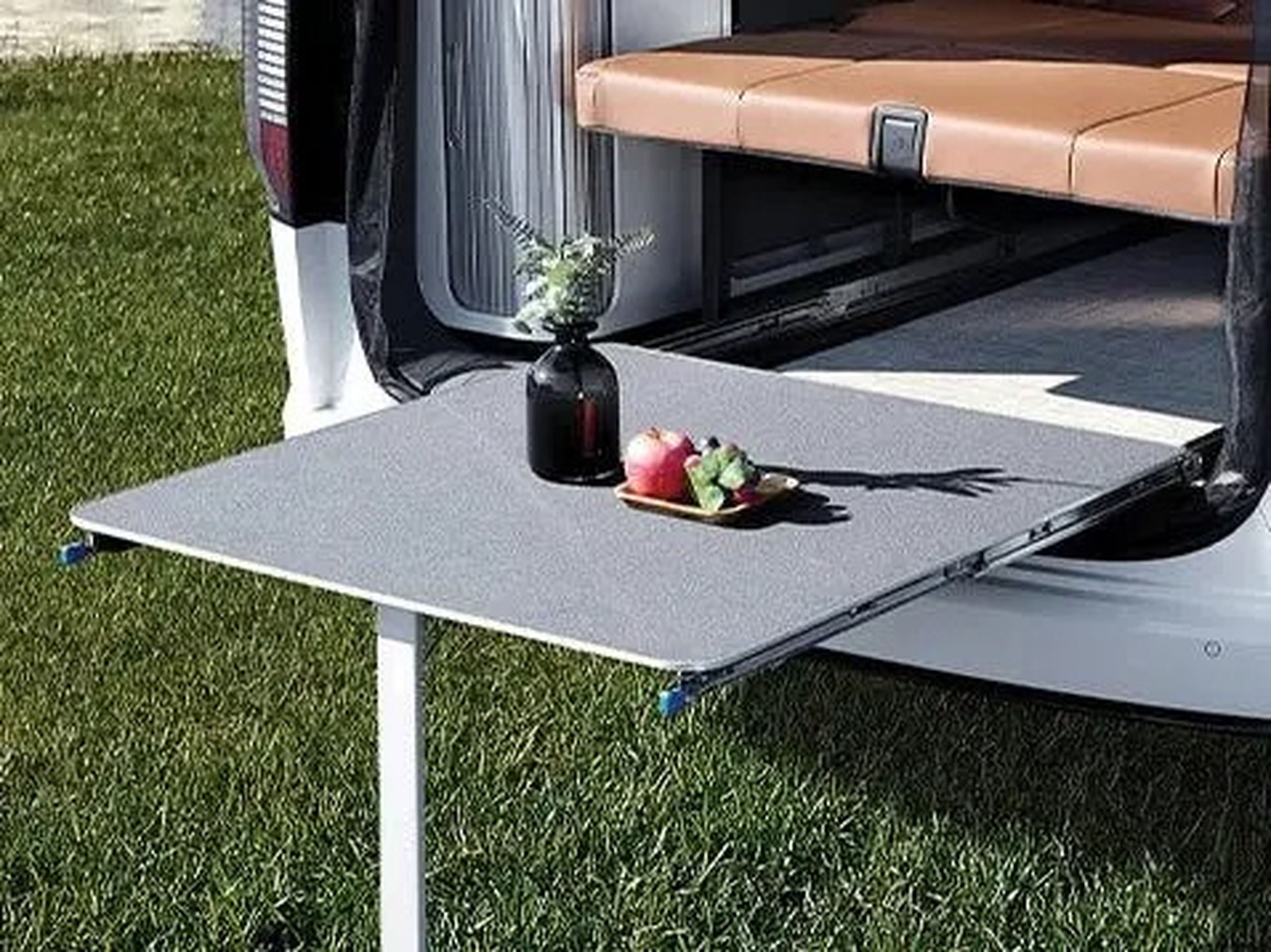 The Hyundai Staria Lounge Camper's exterior table hanging out the back of the minivan.