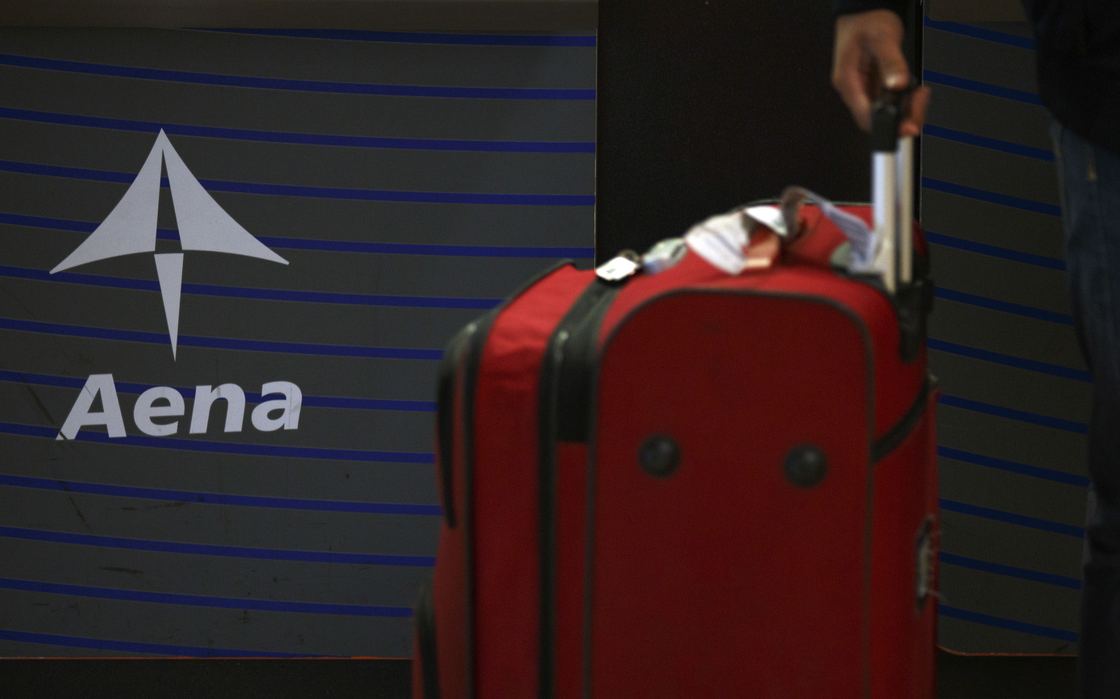 Una maleta en el aeropuerto de Madrid Barajas con el logotipo de Aena de fondo