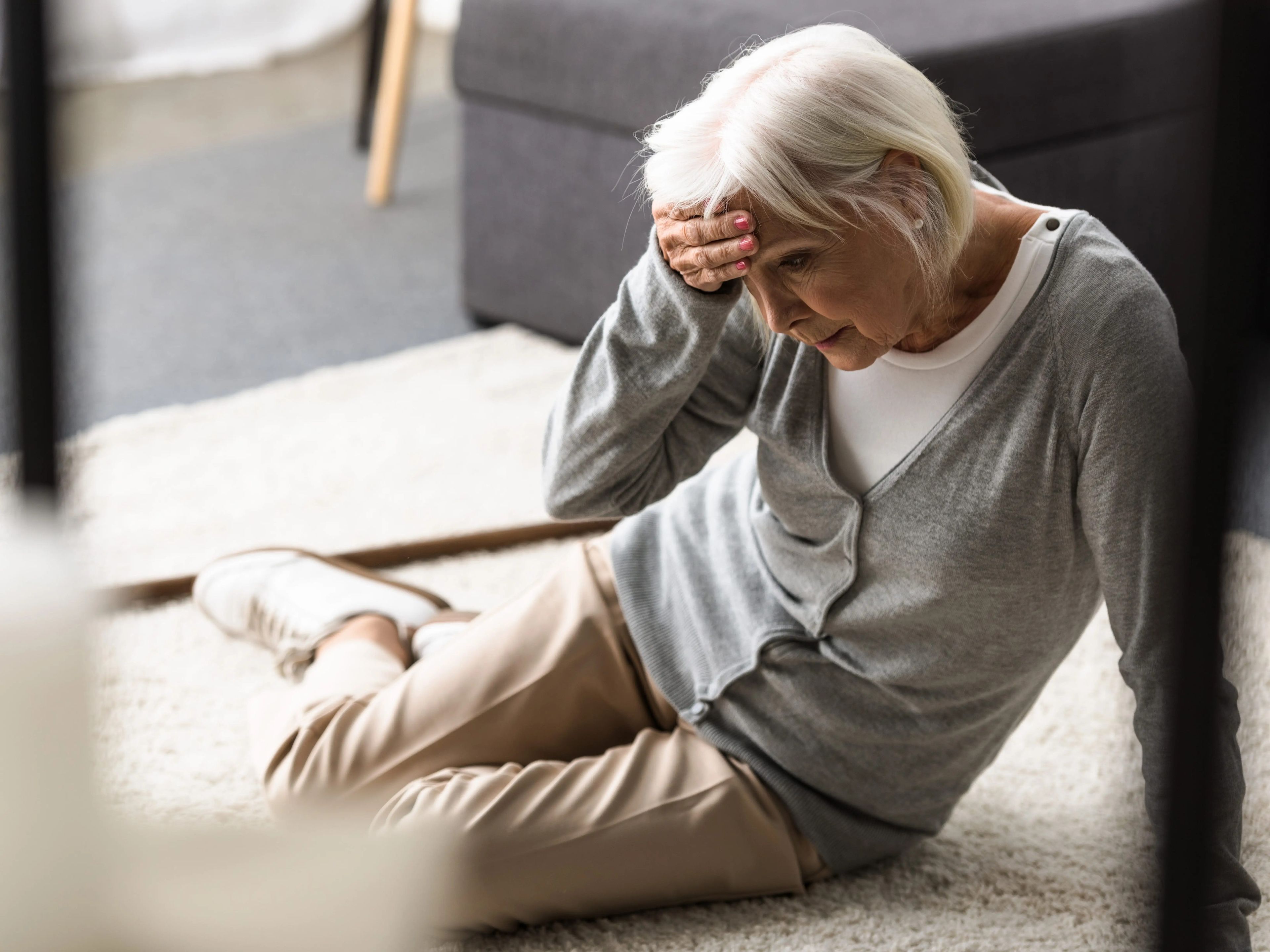 older woman falling down on floor holding her head