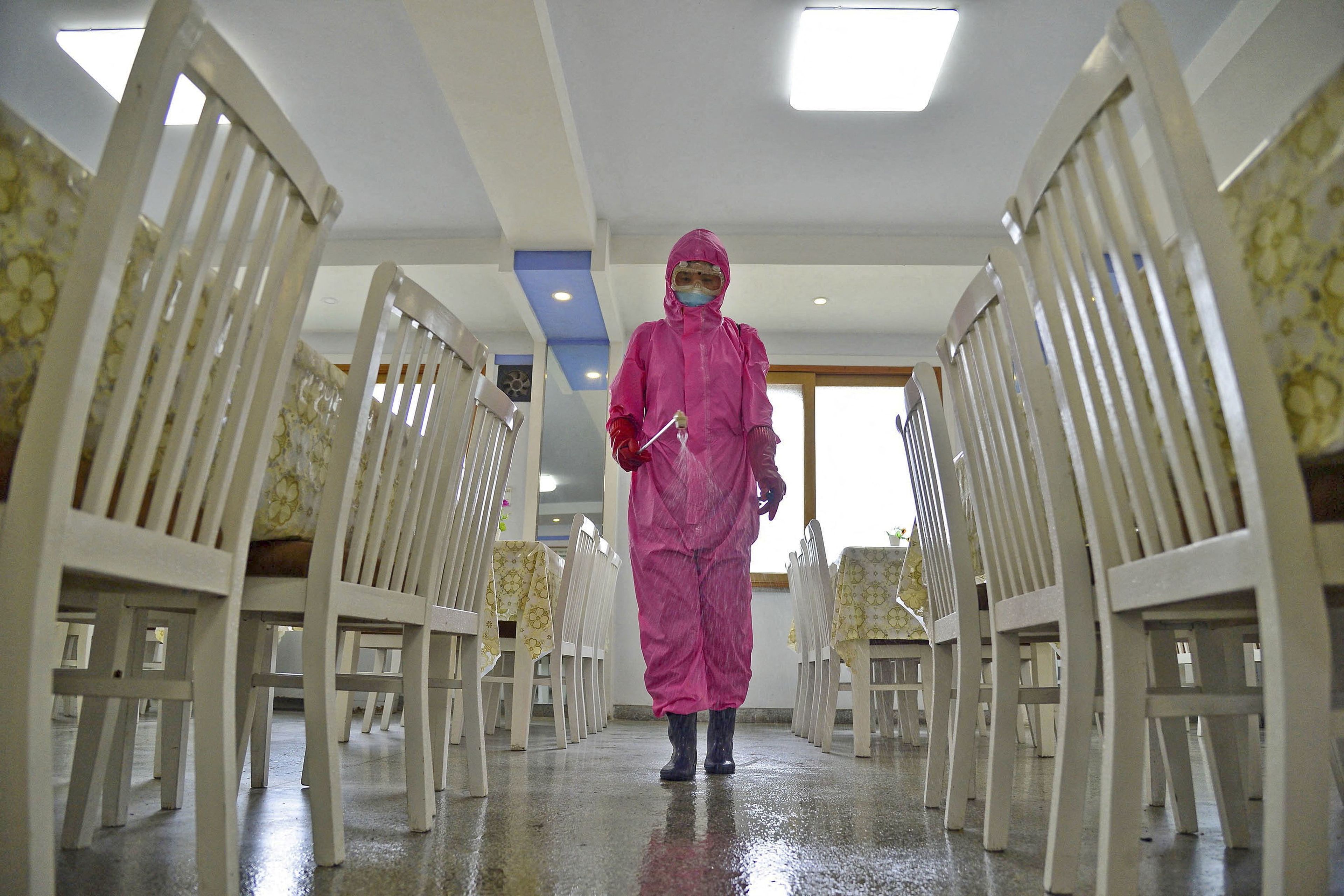 pandemia covid-19, trabajador sanitario desinfecta una clase en Corea del Norte