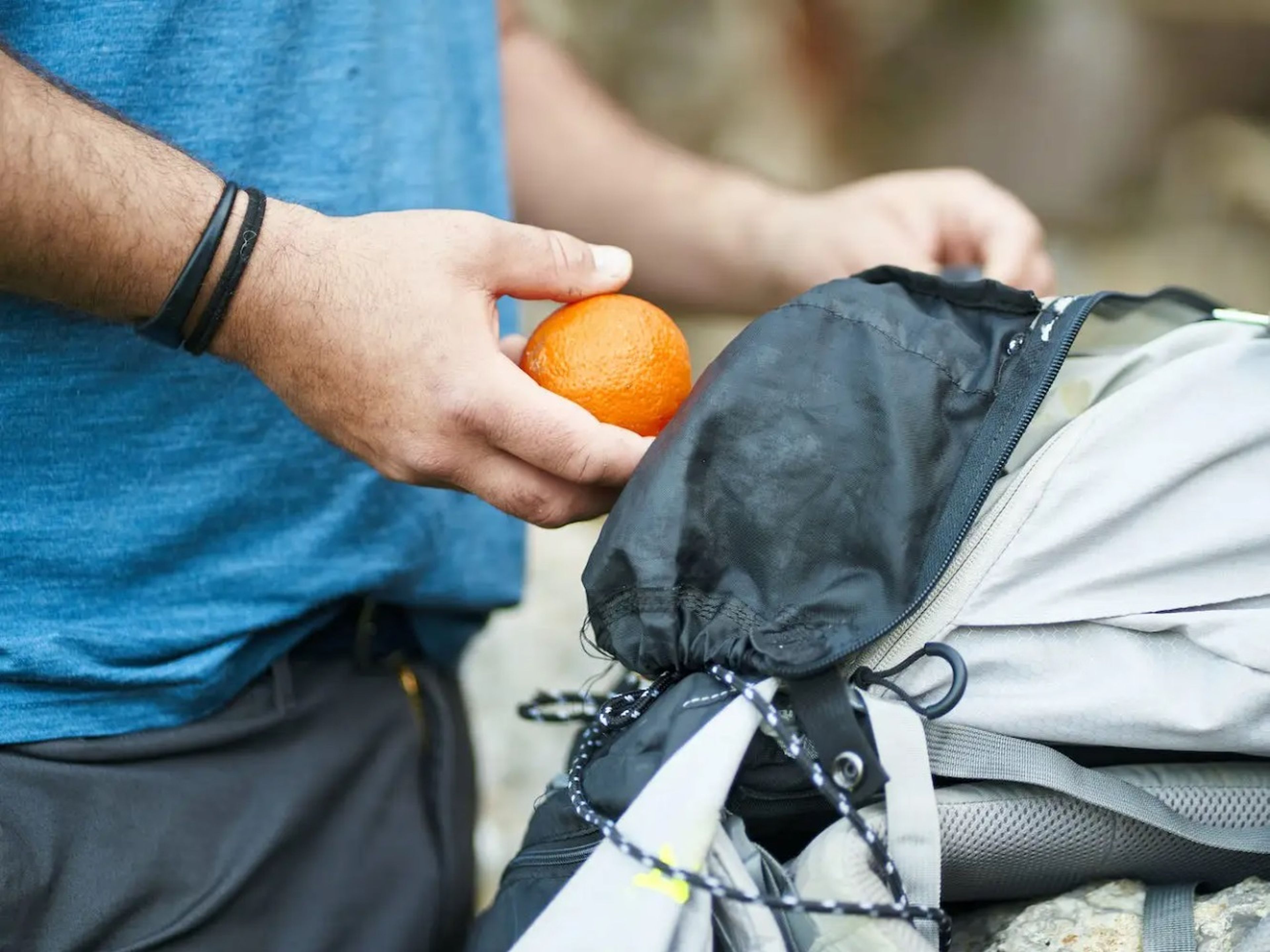 Una persona mete una naranja en su mochila.