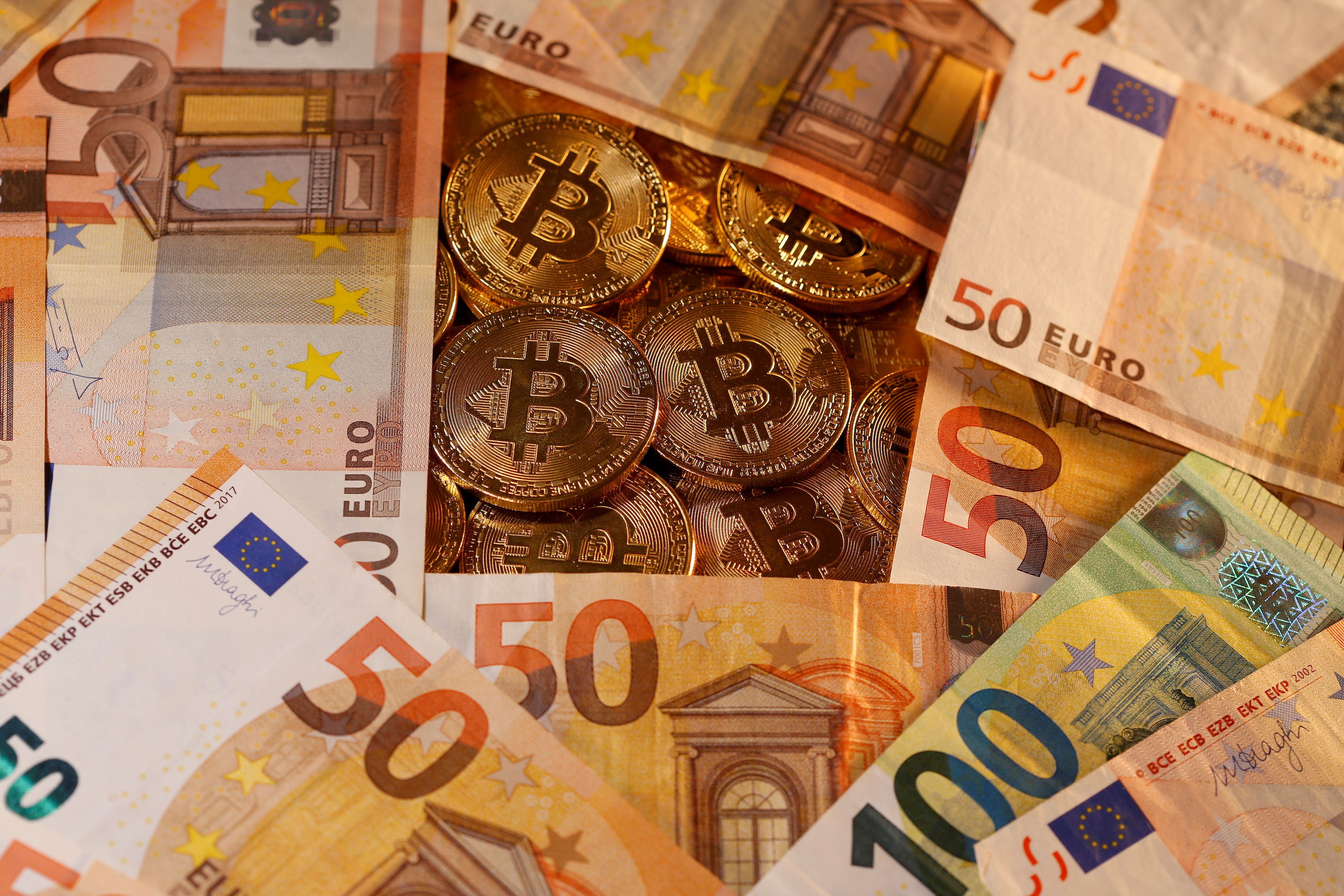 Representación del bitcoin junto a billetes de euro