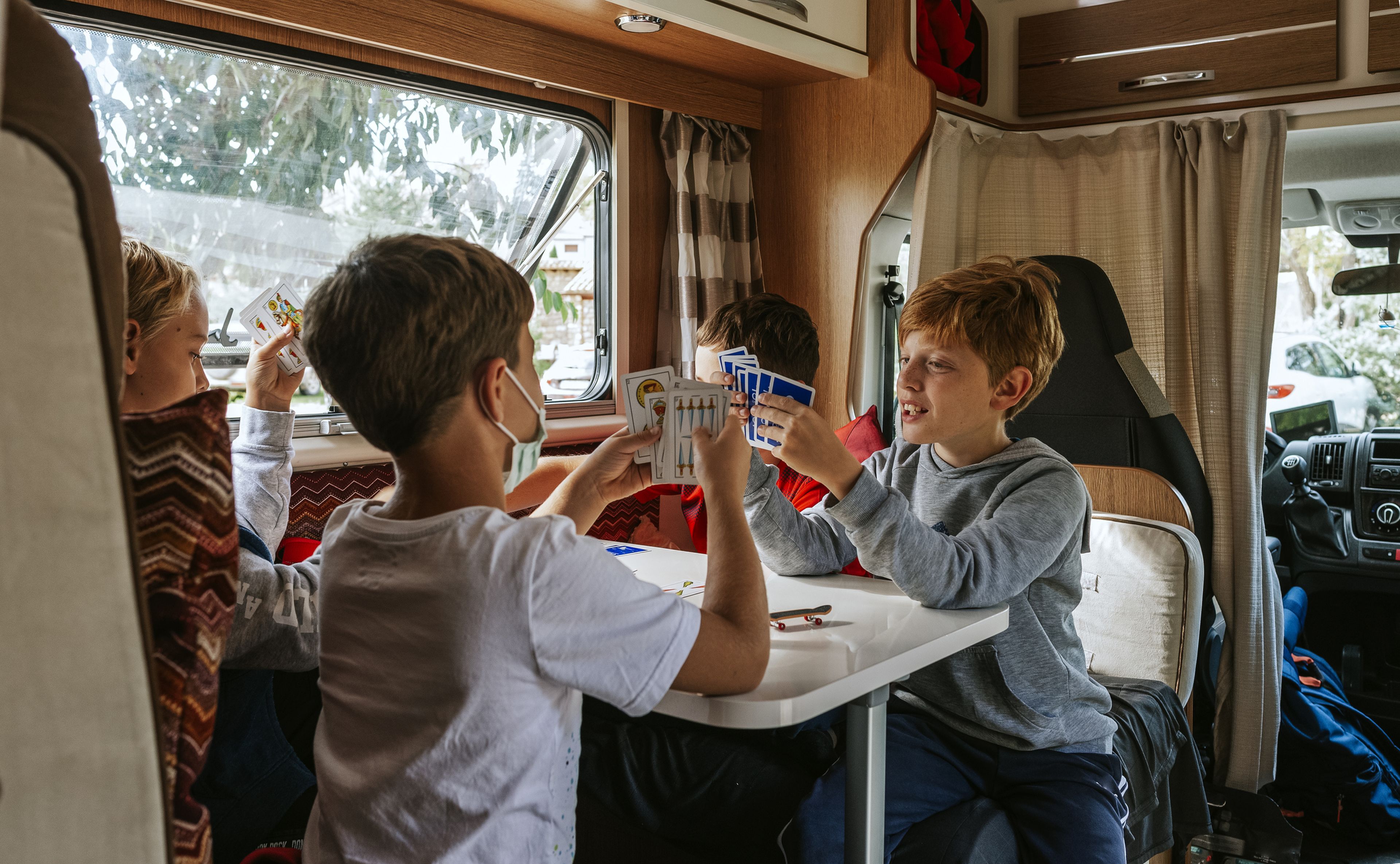 Varios niños juegan a la cartas en una autocaravana.